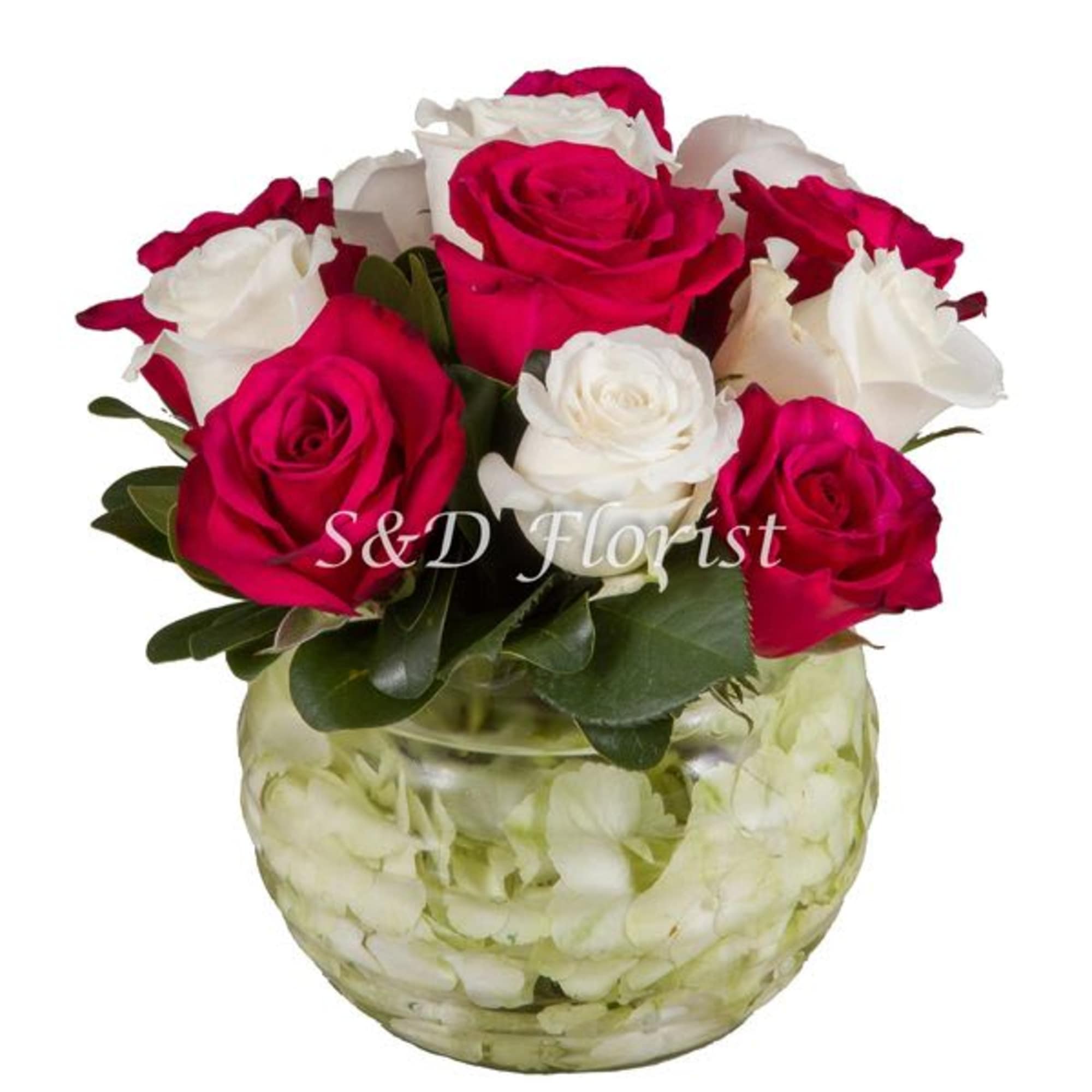 Pink and white roses in a glass vase filled with pale petals