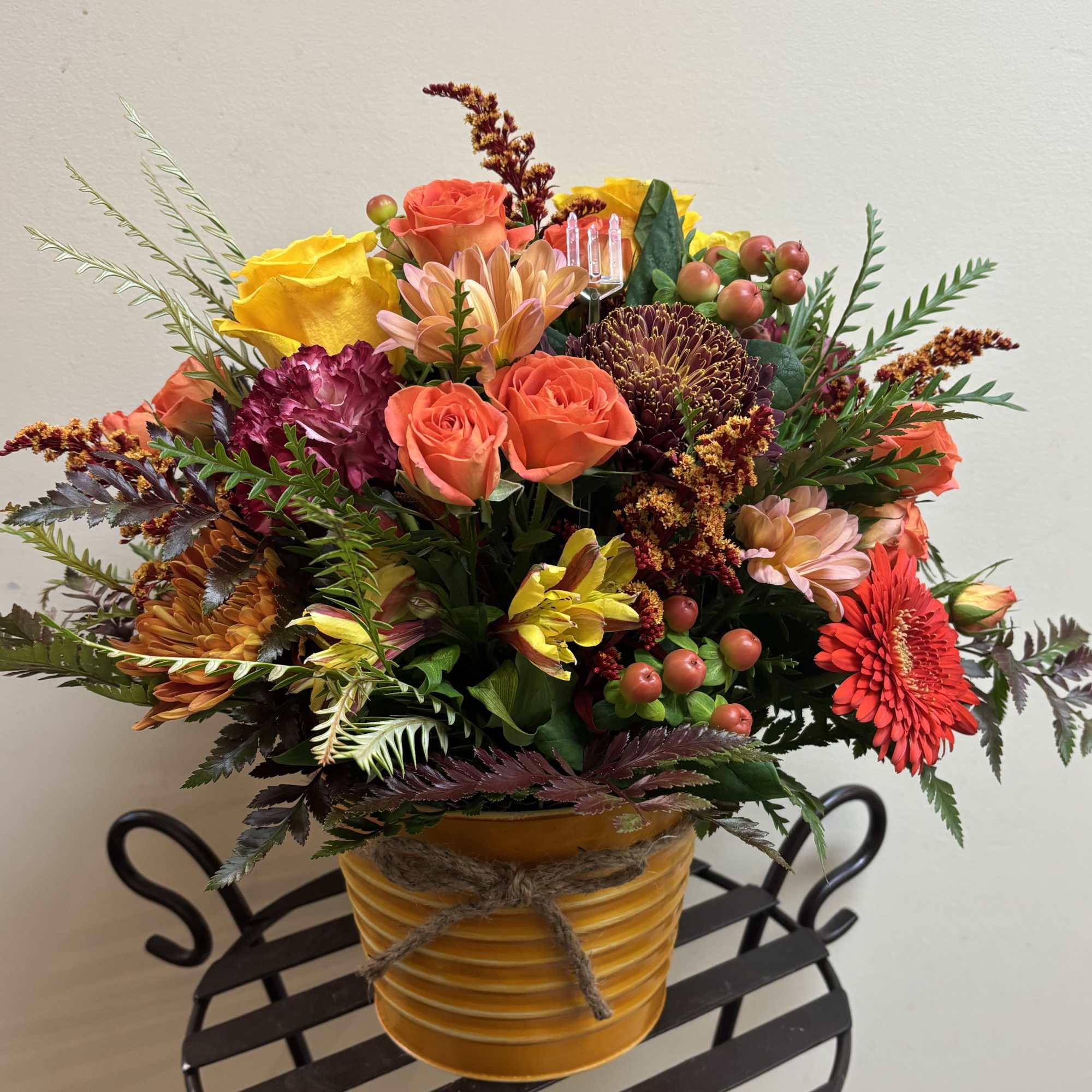 Mixed bouquet in a yellow ribbed pot with orange and yellow blooms
