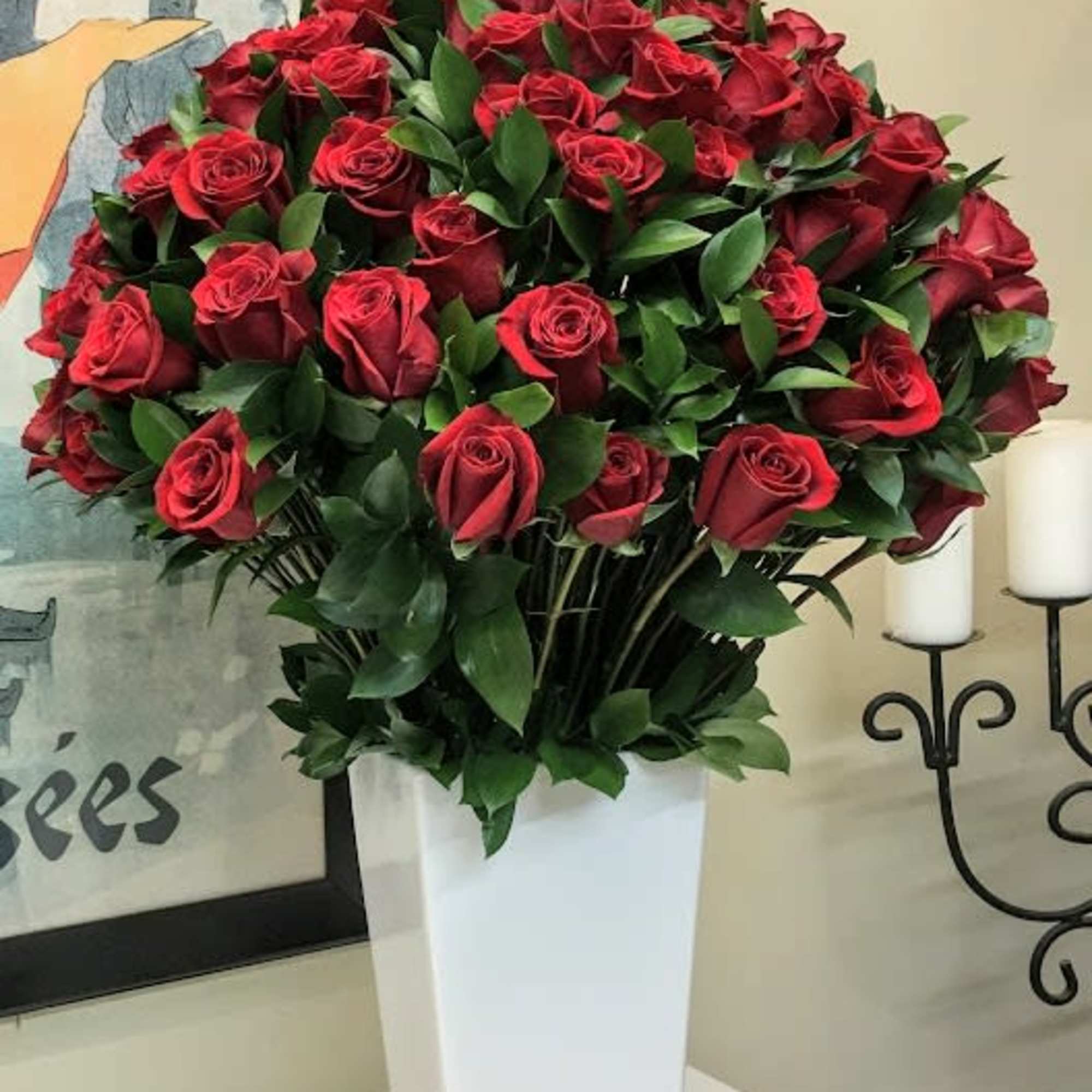 Red roses arranged in a tall white vase