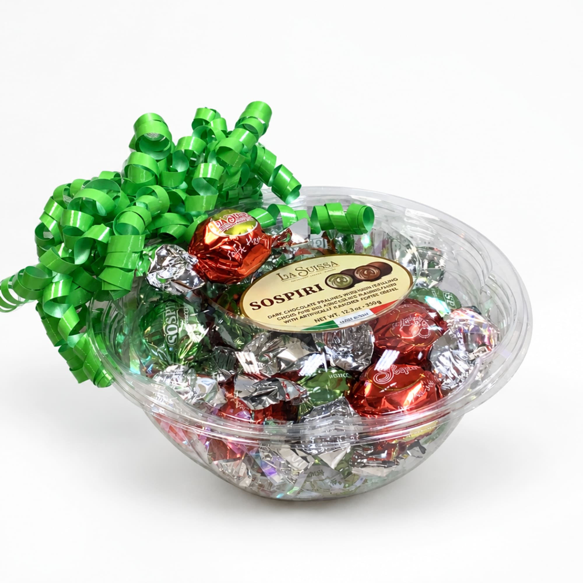 Clear bowl of assorted wrapped chocolates topped with a green curly ribbon