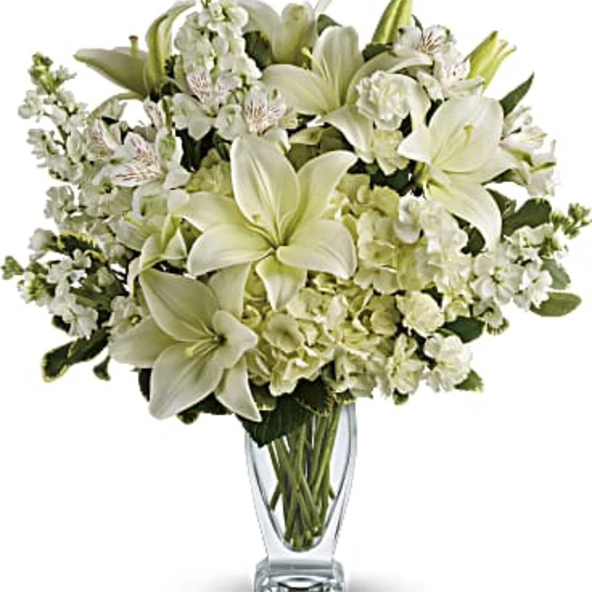 White lilies and pale blooms arranged in a clear glass vase.