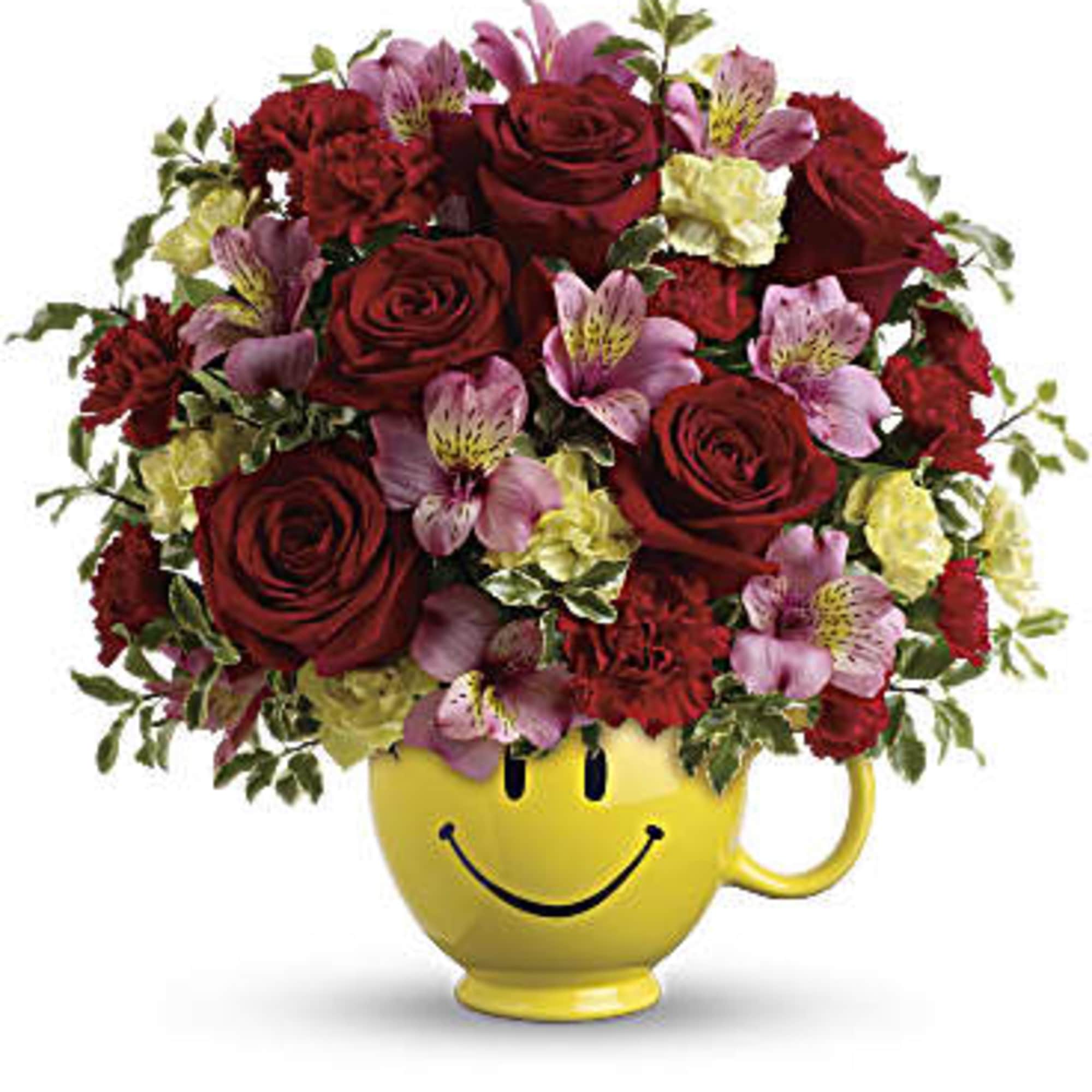 Red roses and pink flowers in a yellow smiley-face mug