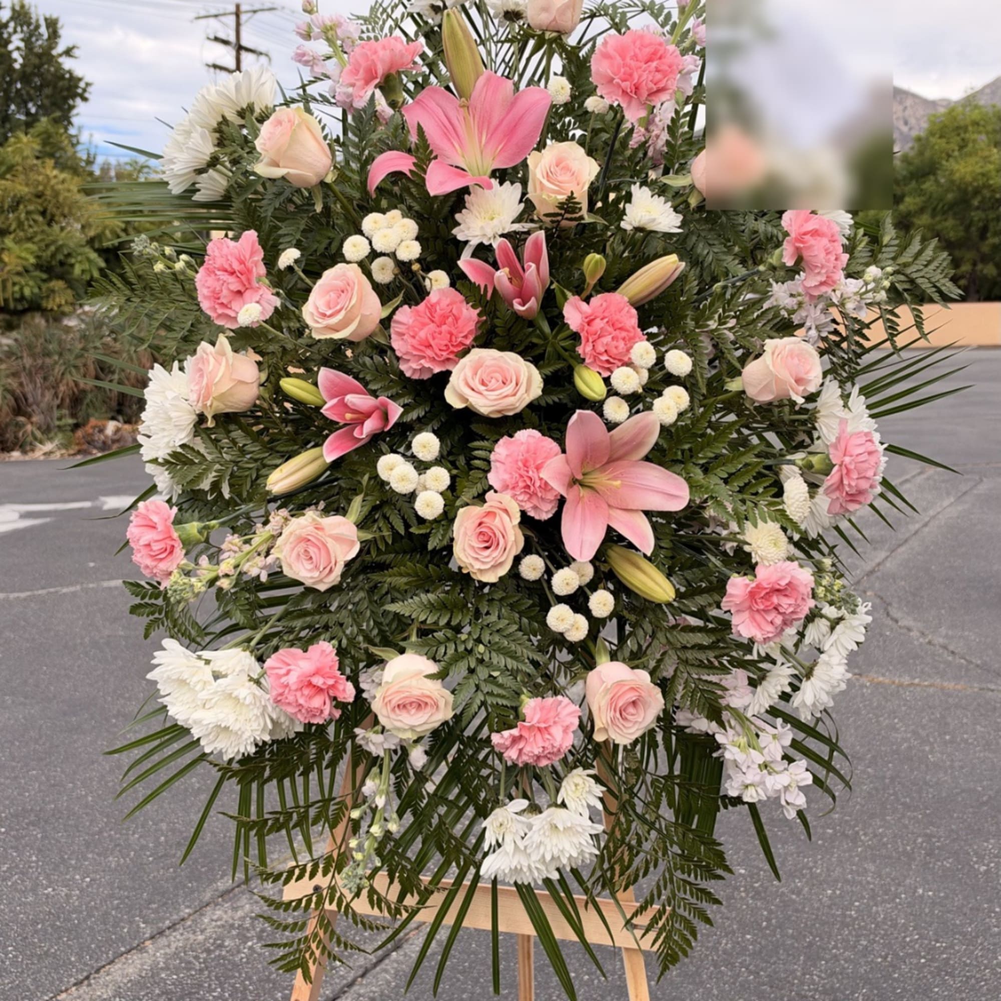 Large pink and white floral standing arrangement on an easel
