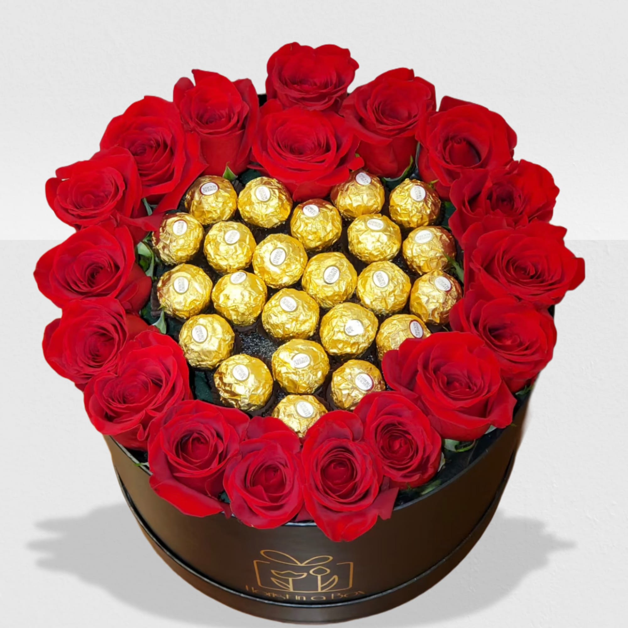 Round black hatbox with red roses encircling gold-wrapped chocolates