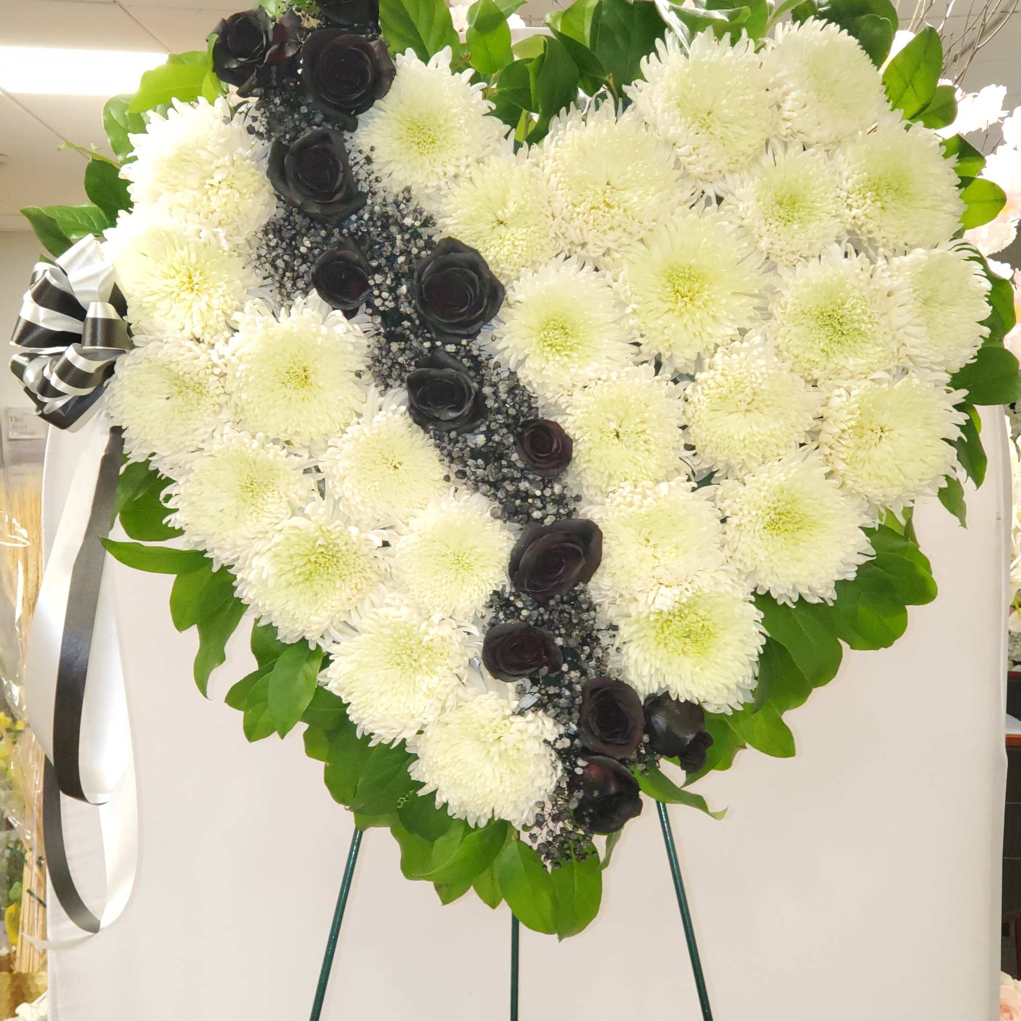 Heart-shaped white chrysanthemum wreath with black roses and ribbon