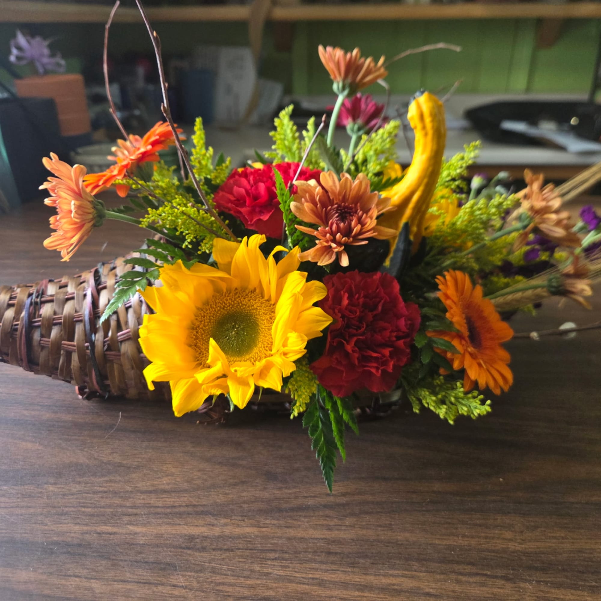 Mixed bouquet with sunflowers, chrysanthemums, and orange blooms in a woven basket