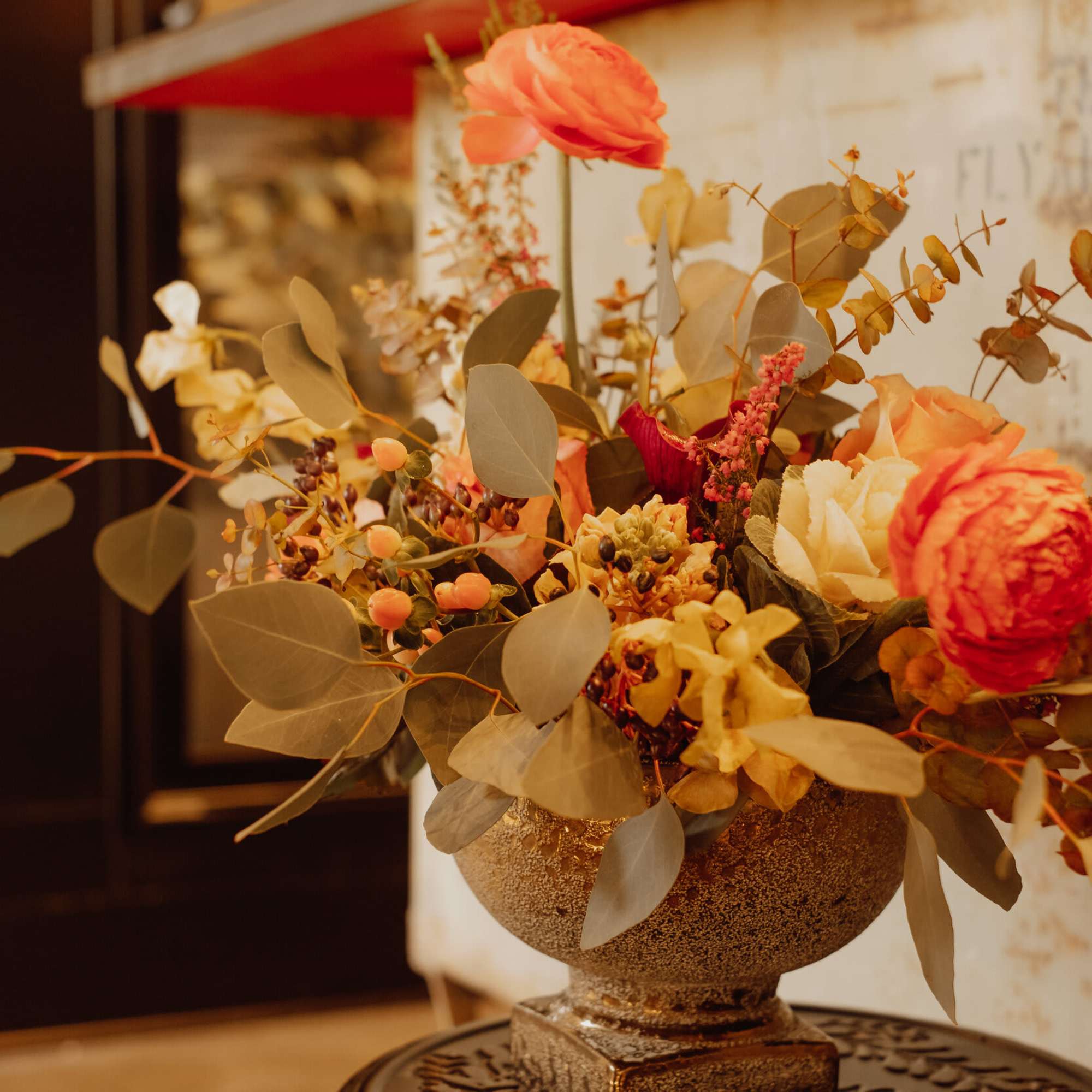 Arrangement of orange and cream flowers in a textured vase
