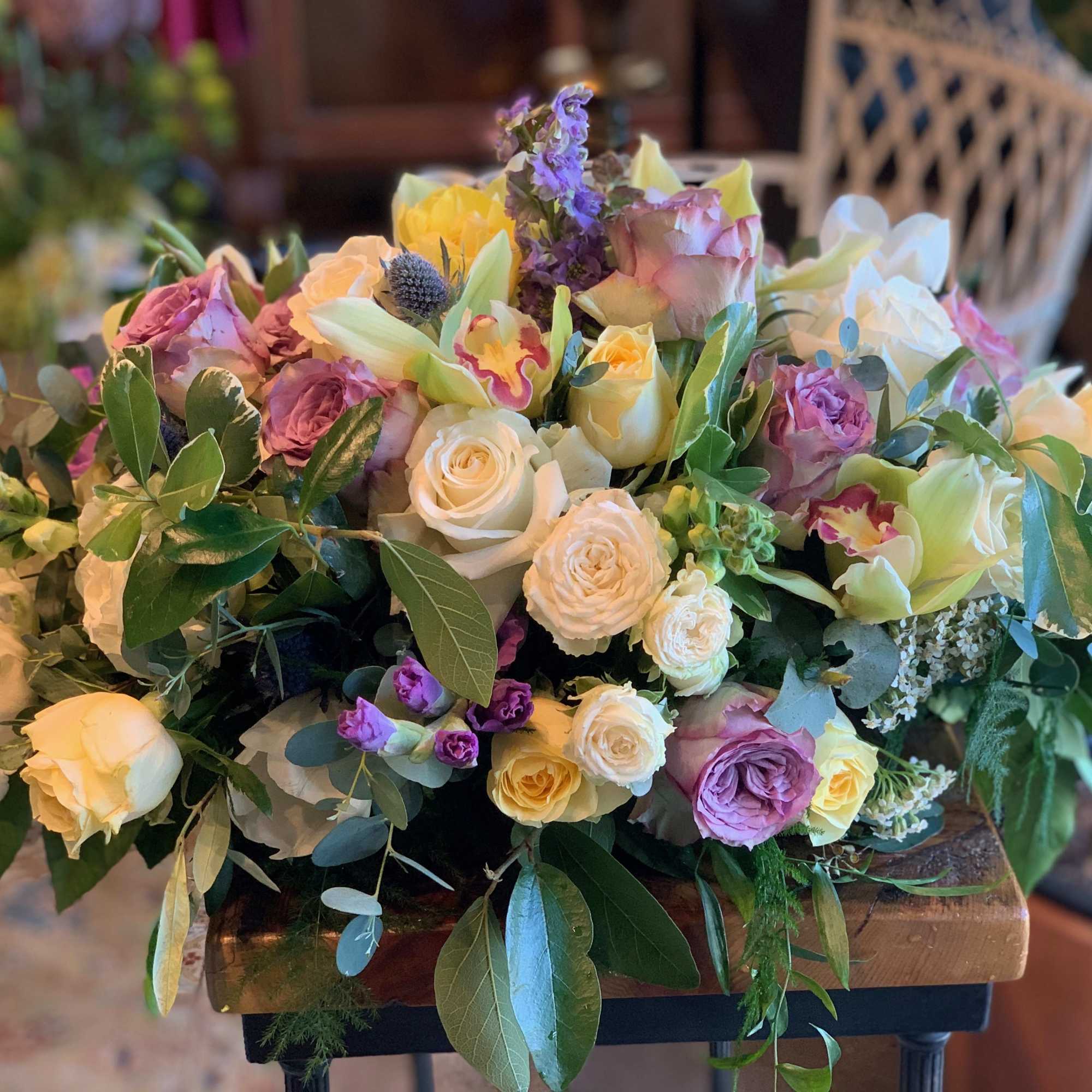 Low floral centerpiece with roses, lilies, and mixed blooms in pastel colors