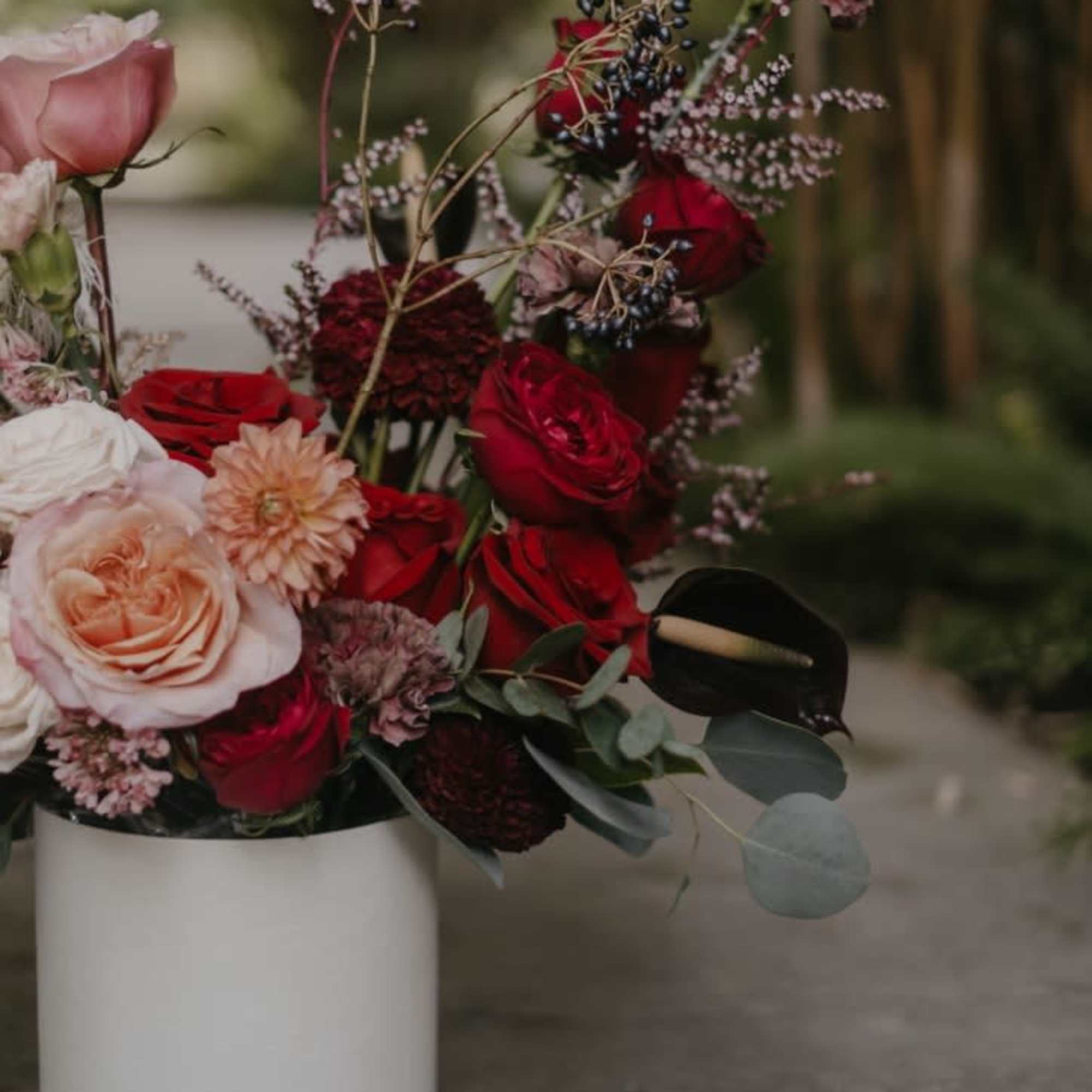 Bouquet of red and blush roses in a white cylindrical vase