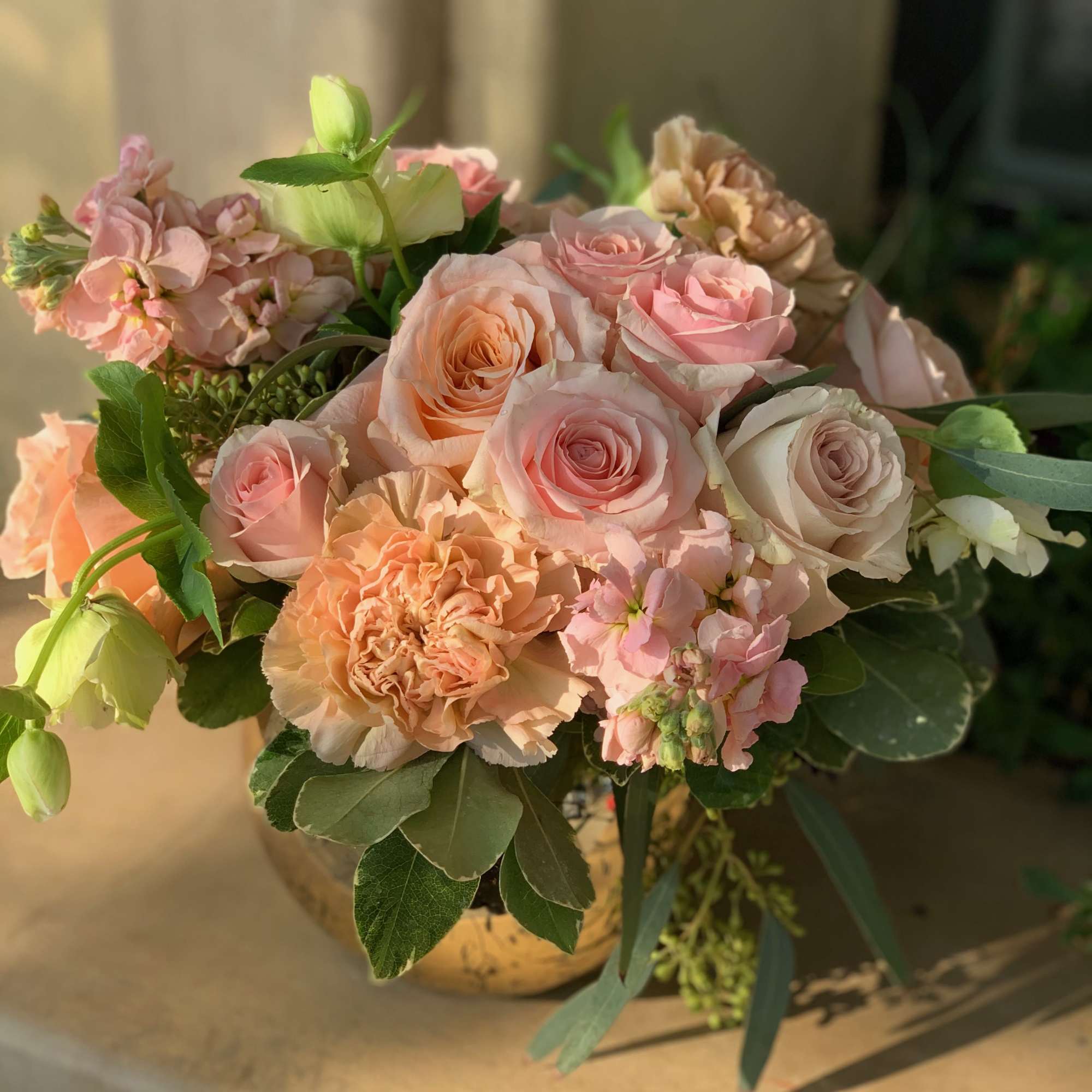 Bouquet of blush and peach roses with carnations in a gold vase