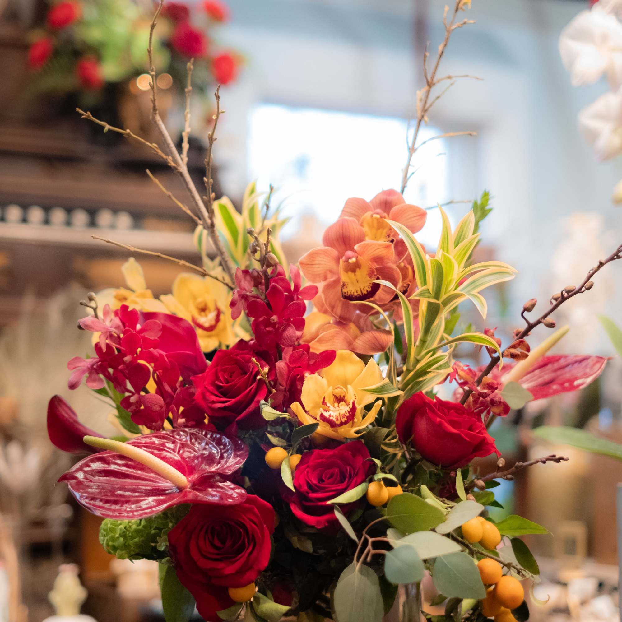 Mixed bouquet with red roses and orchids in a square vase