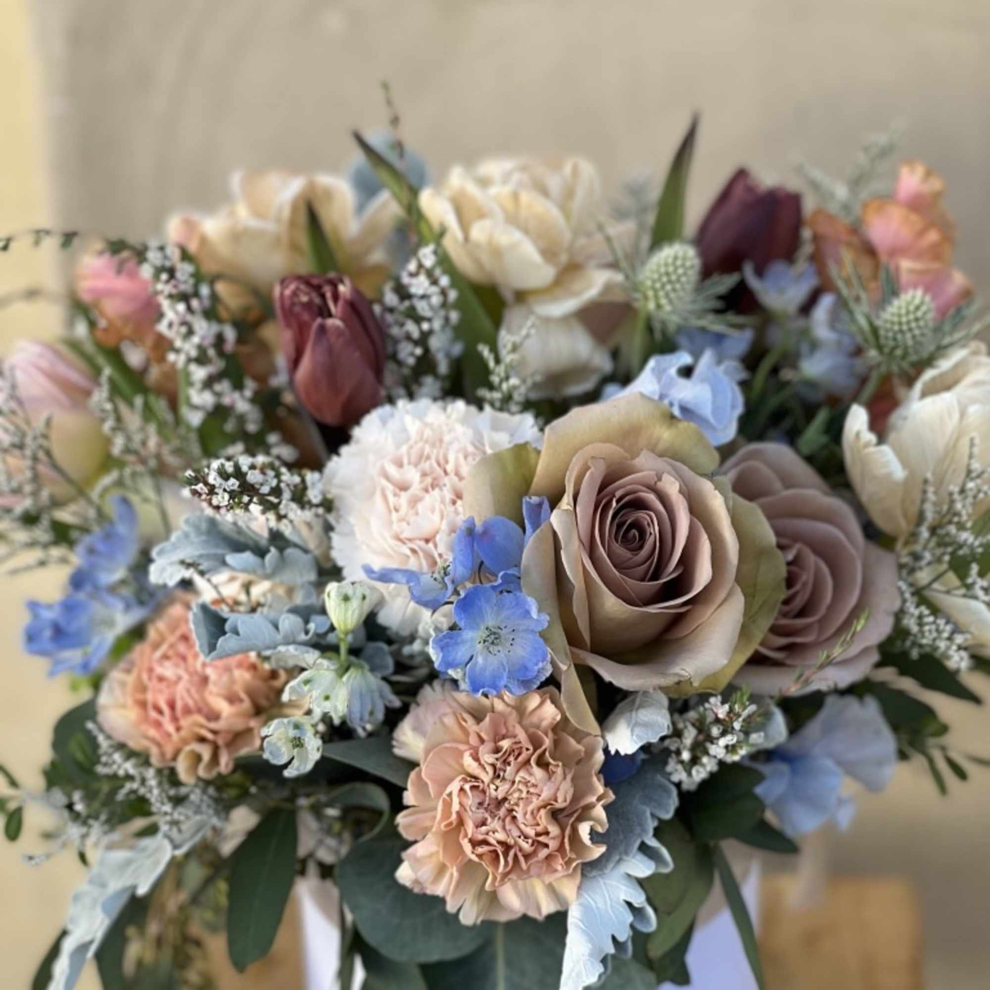 Bouquet of pastel roses, tulips, carnations, and blue flowers