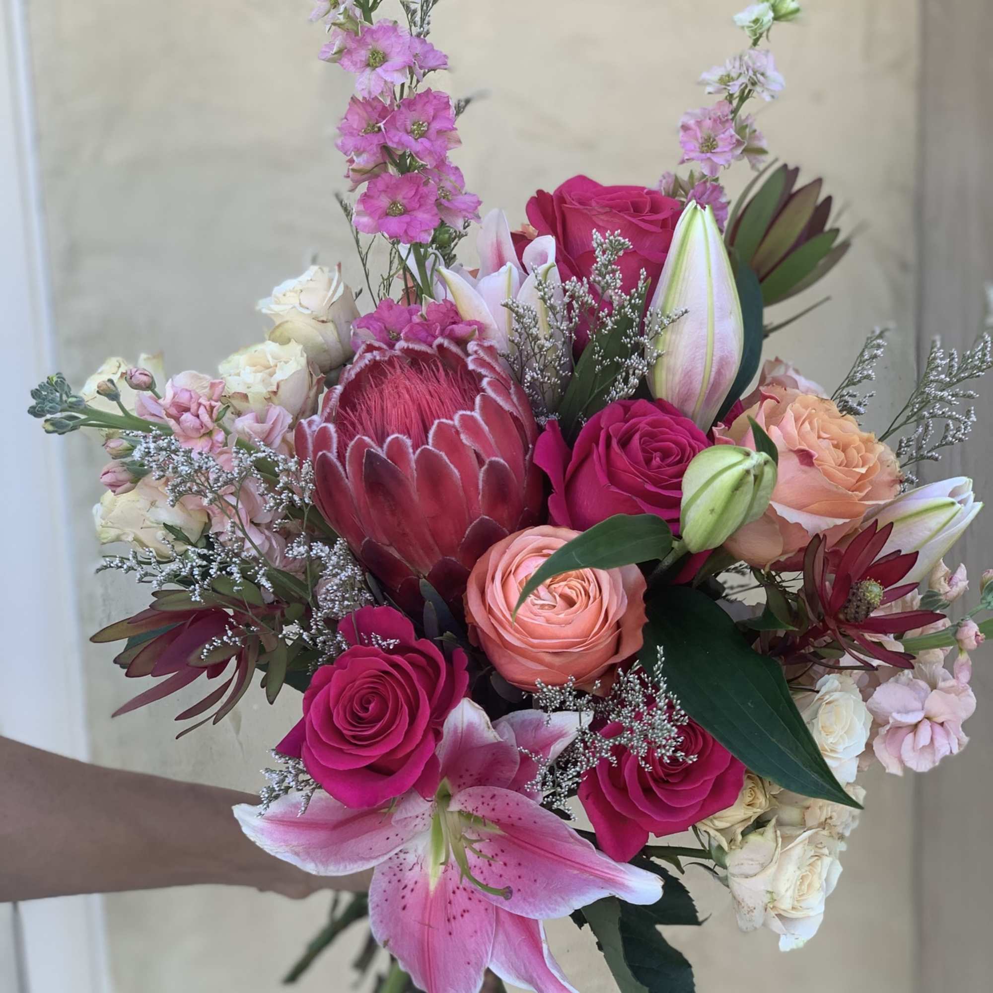 Hand-tied bouquet of pink roses, lilies, and protea