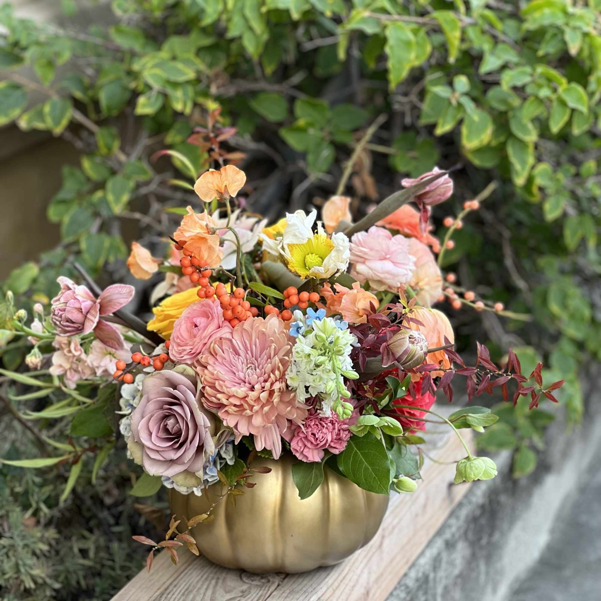 Mixed pastel flower arrangement in a gold pumpkin vase