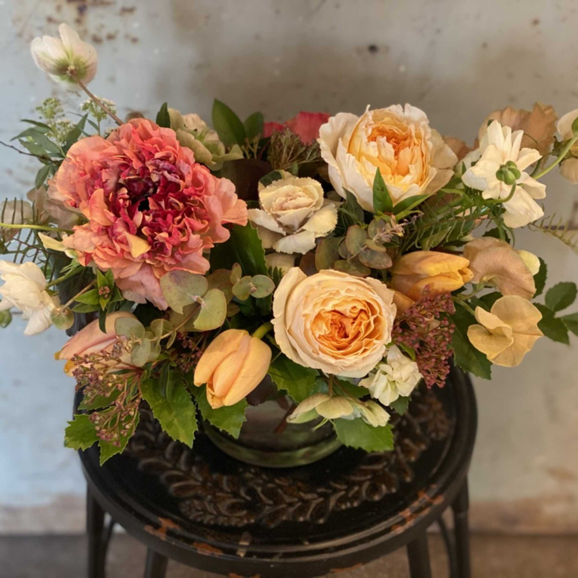 Mixed bouquet of peach, pink, and white flowers in a glass vase