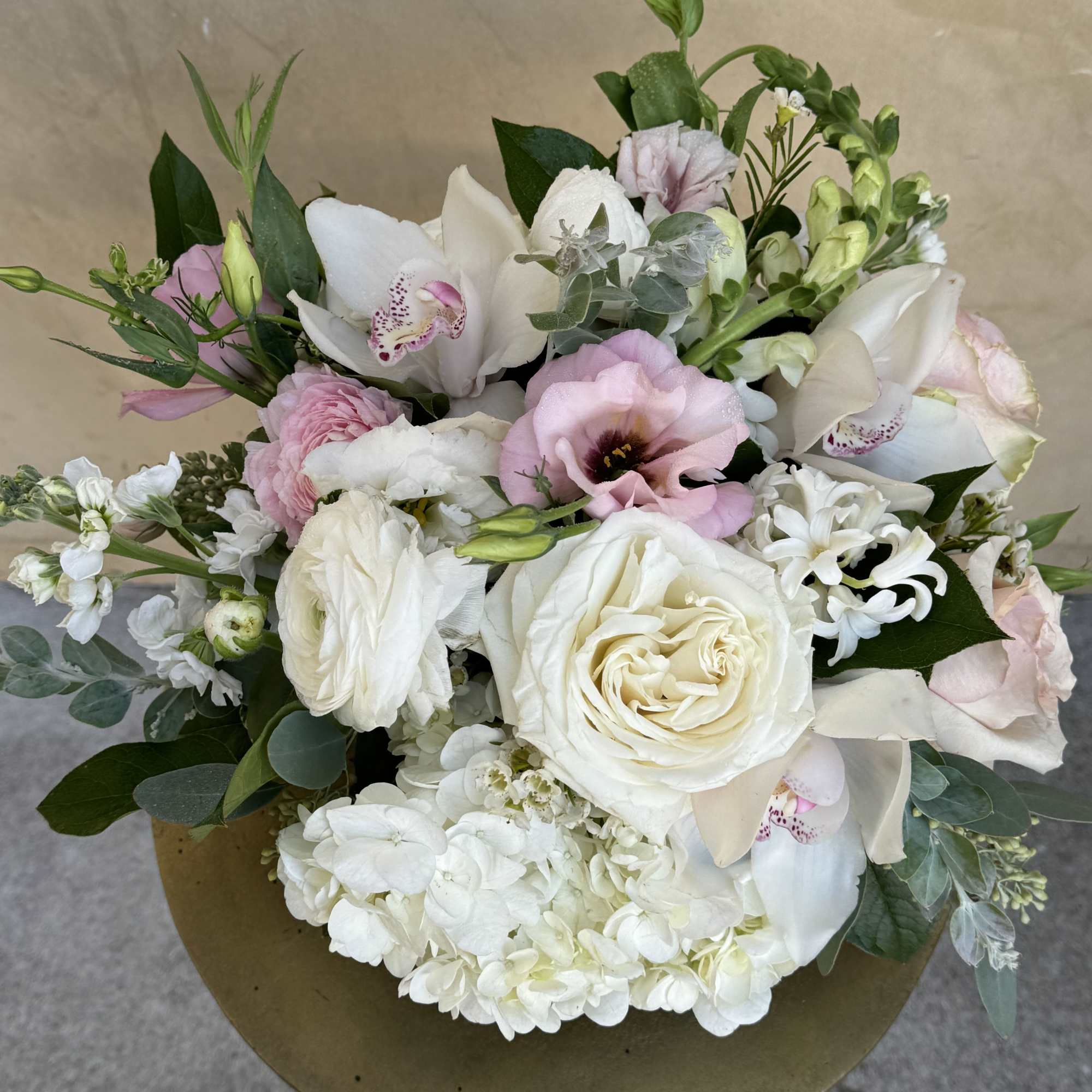 Mixed bouquet of white and blush flowers in a round gold container