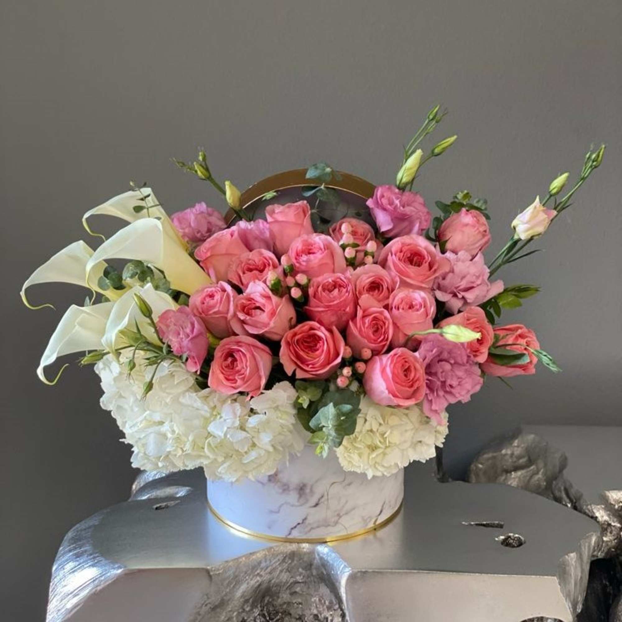 Pink roses and white hydrangeas arranged in a round box
