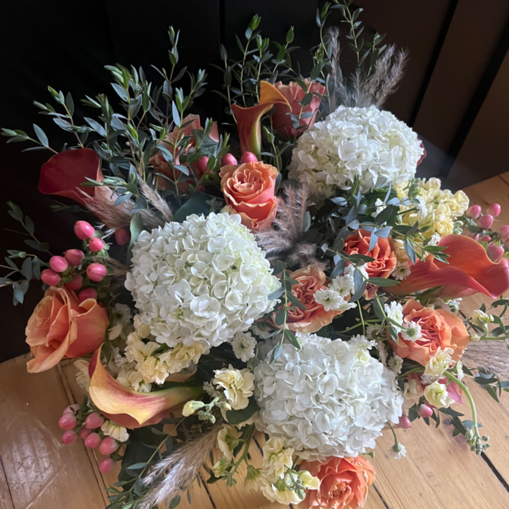 Bouquet of white hydrangeas, peach roses, and orange calla lilies