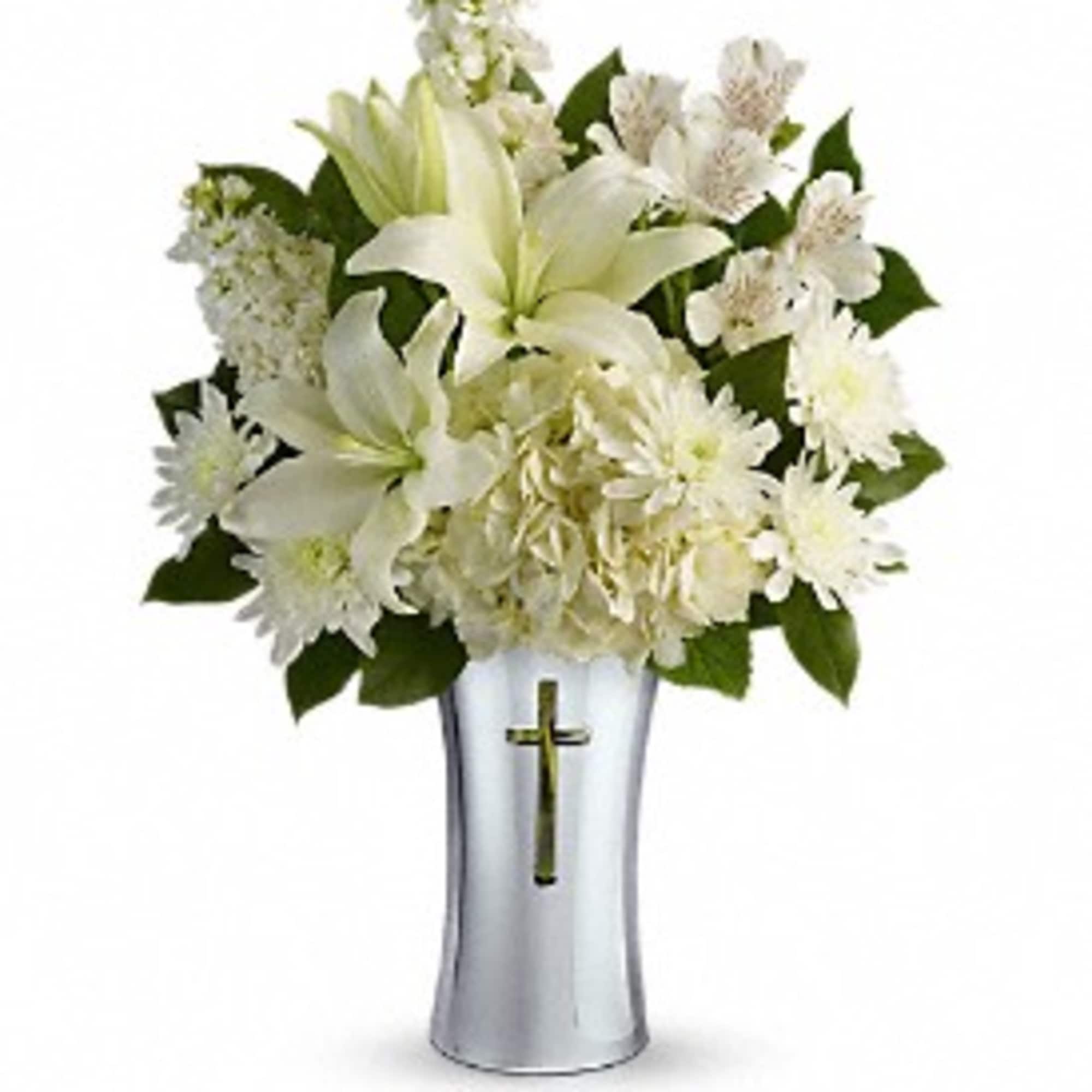 White floral arrangement in a silver vase with a cross emblem