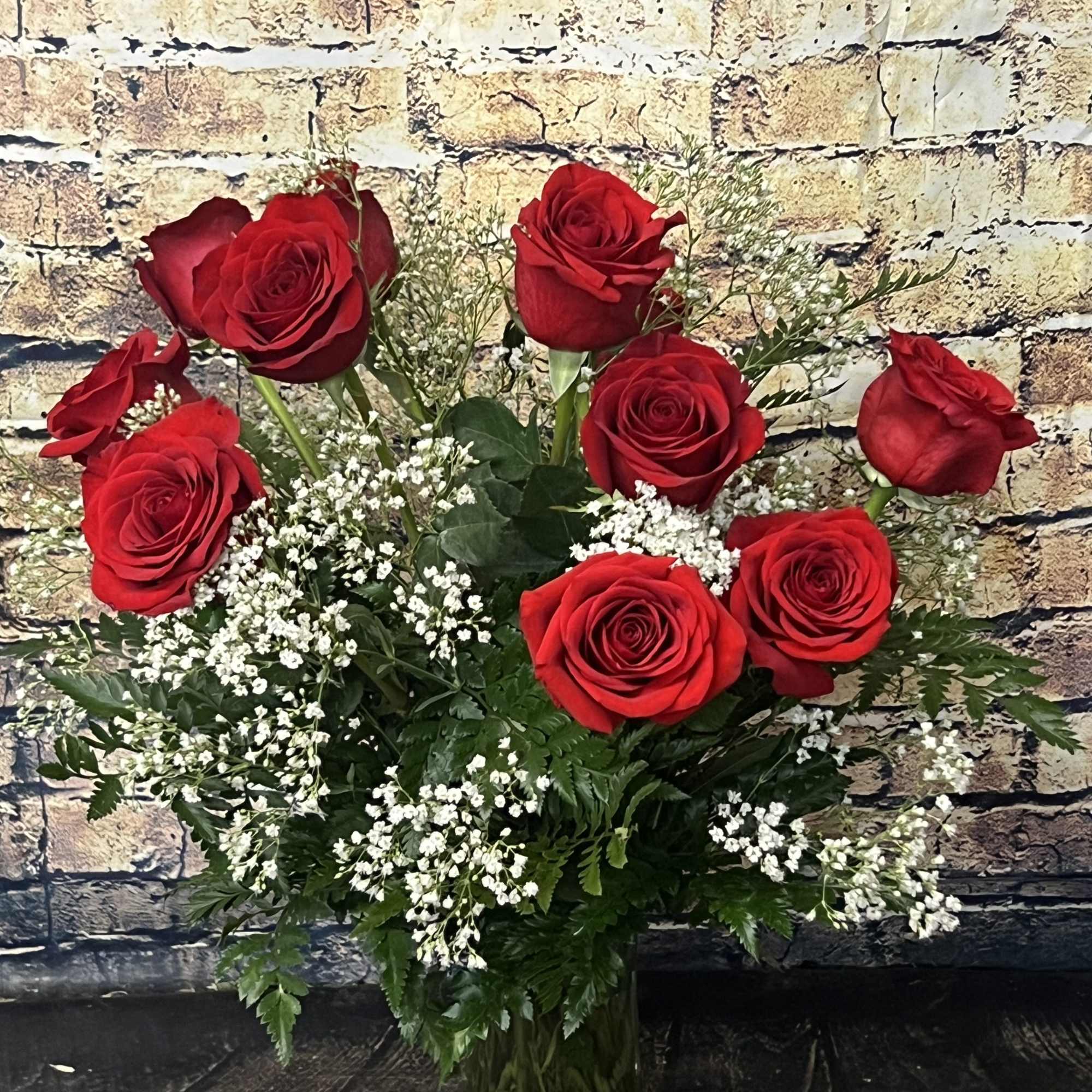 Bouquet of red roses with white filler flowers in a glass vase