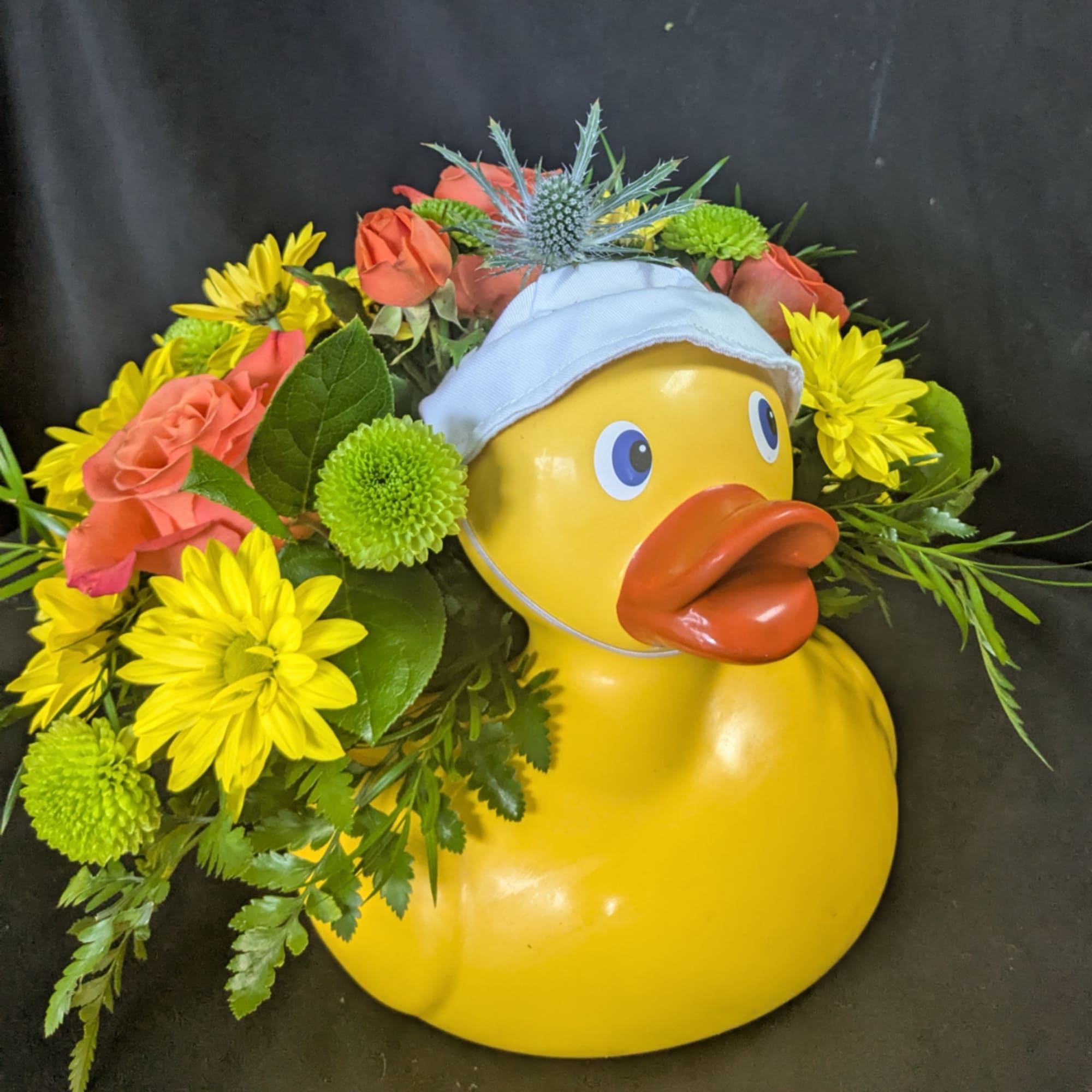 Yellow duck figurine surrounded by yellow and coral flowers