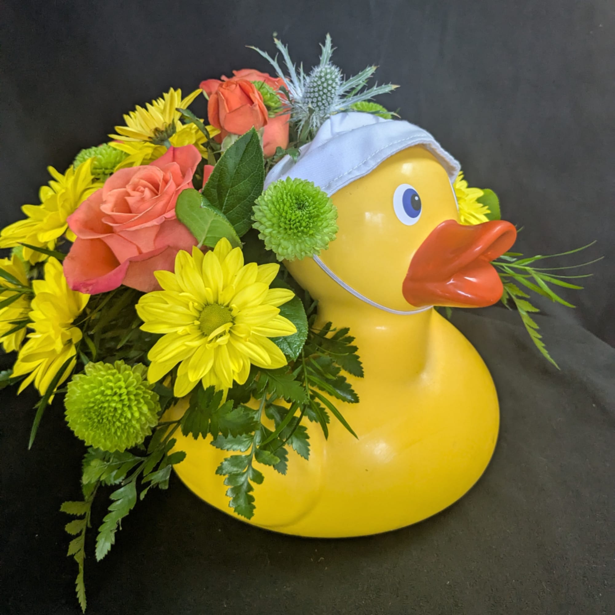Yellow duck planter filled with roses and daisies