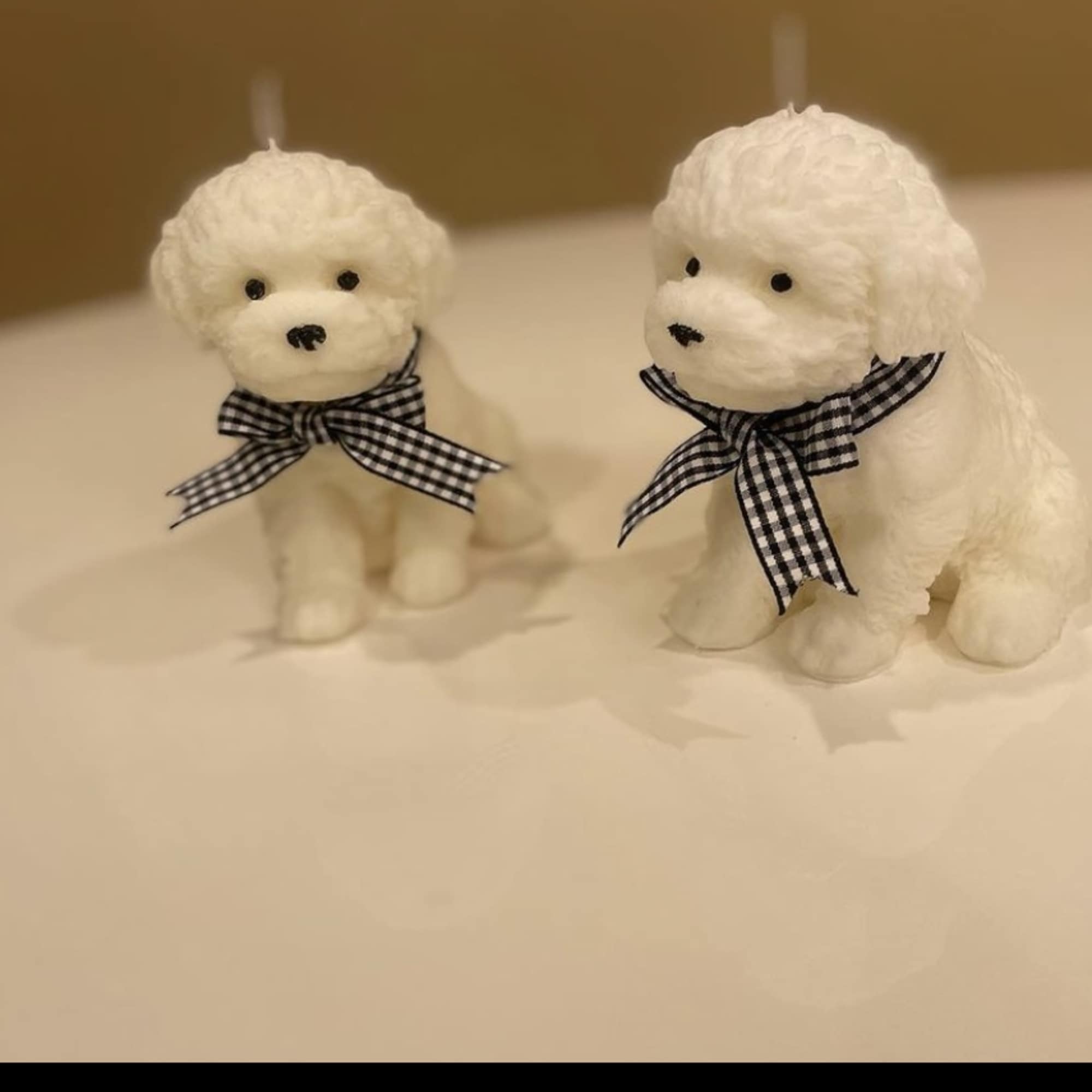 Two small white plush dog figurines with black gingham bows