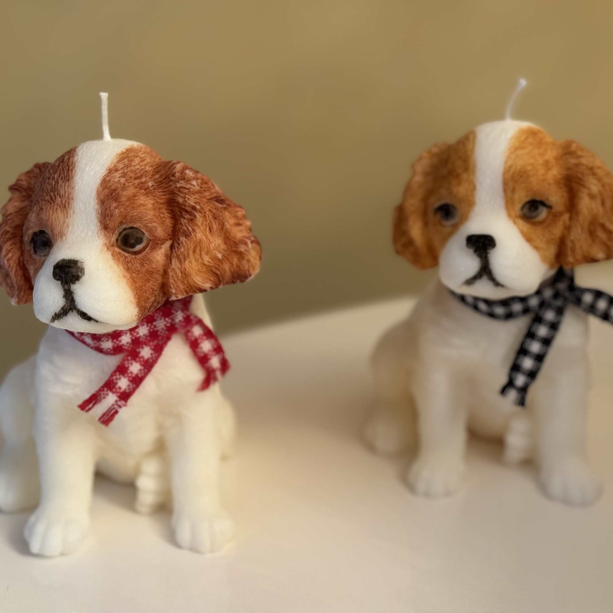 Two dog-shaped candles with scarves on a tabletop