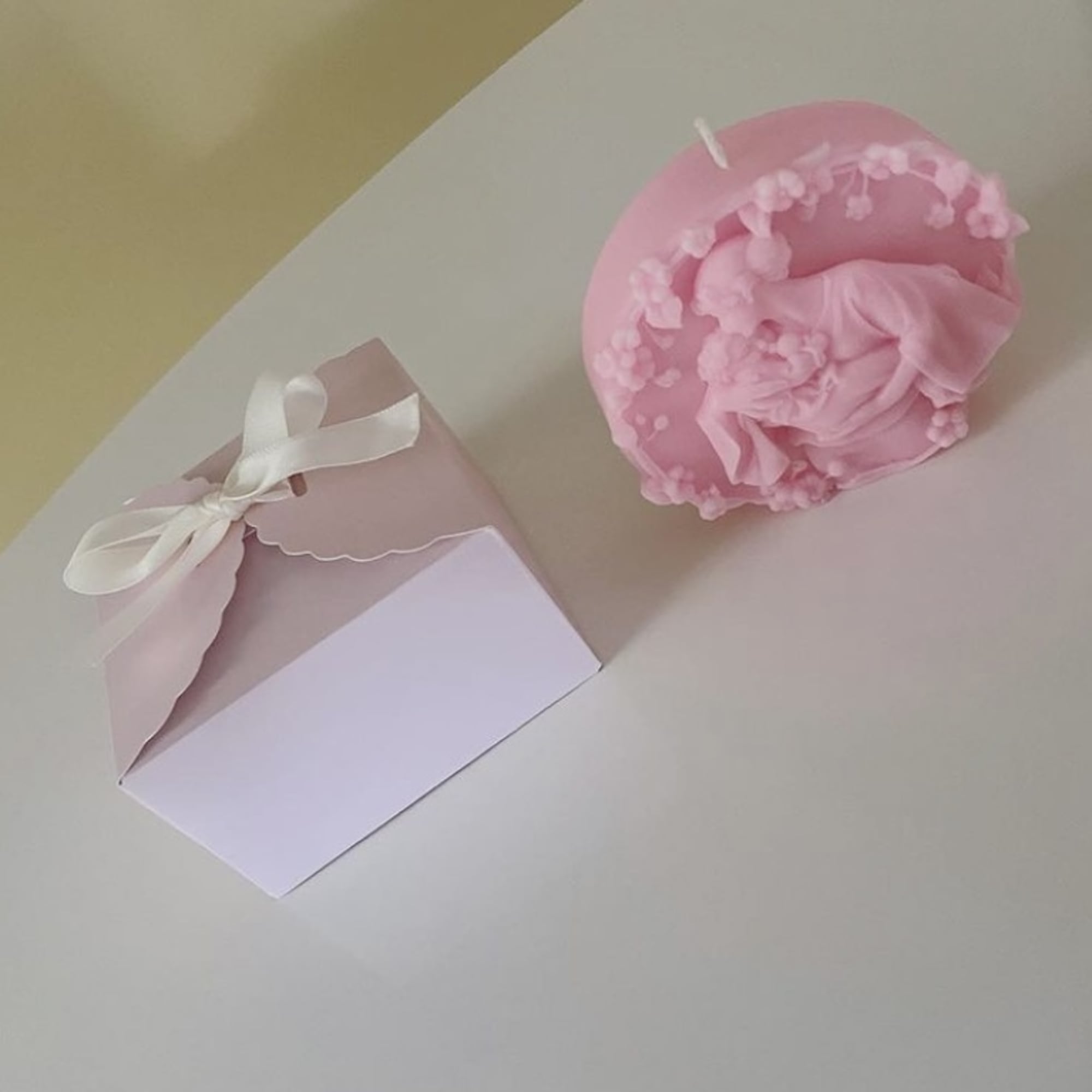 Pink candle and a pink gift box with ribbon