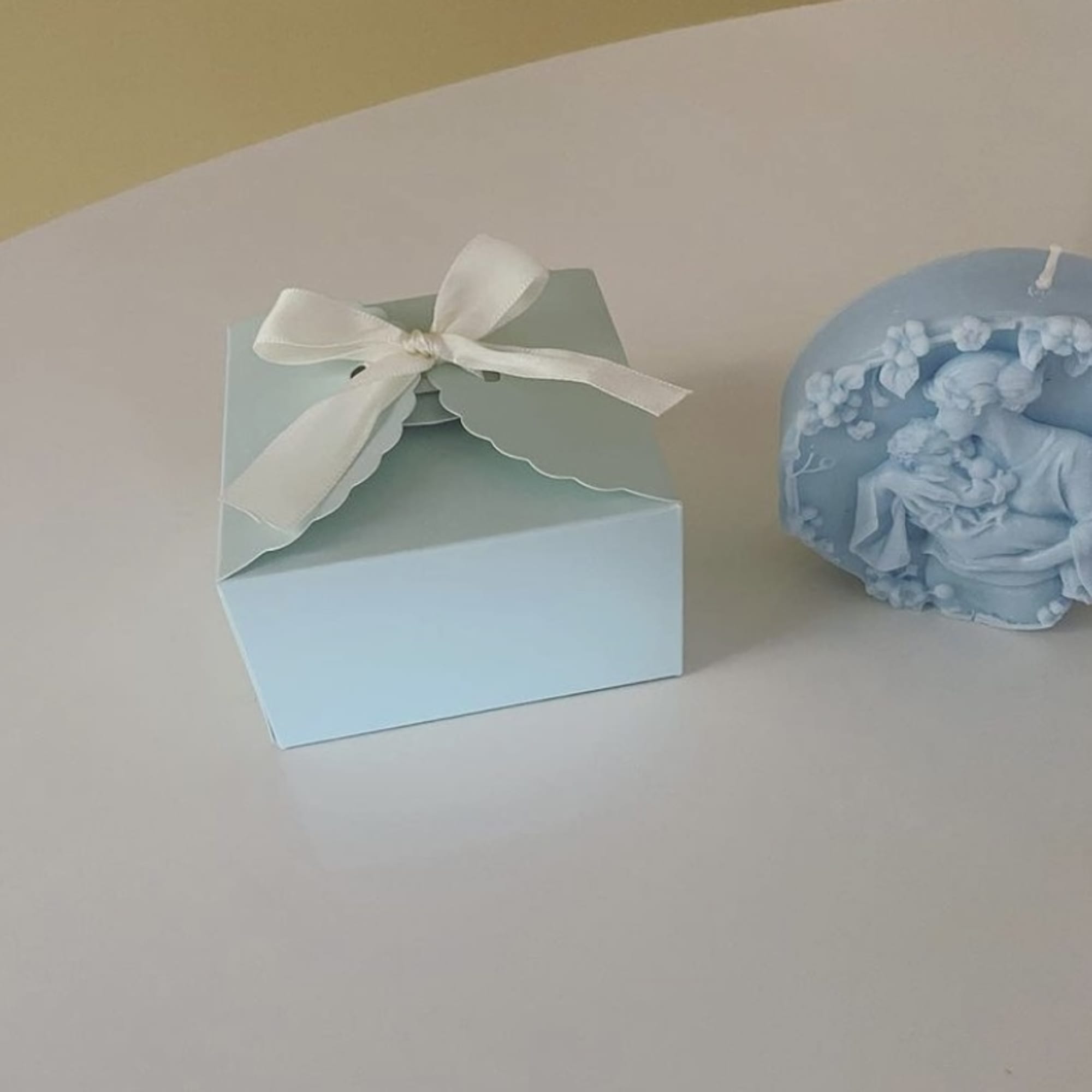 Blue gift box with ribbon beside a blue decorative candle