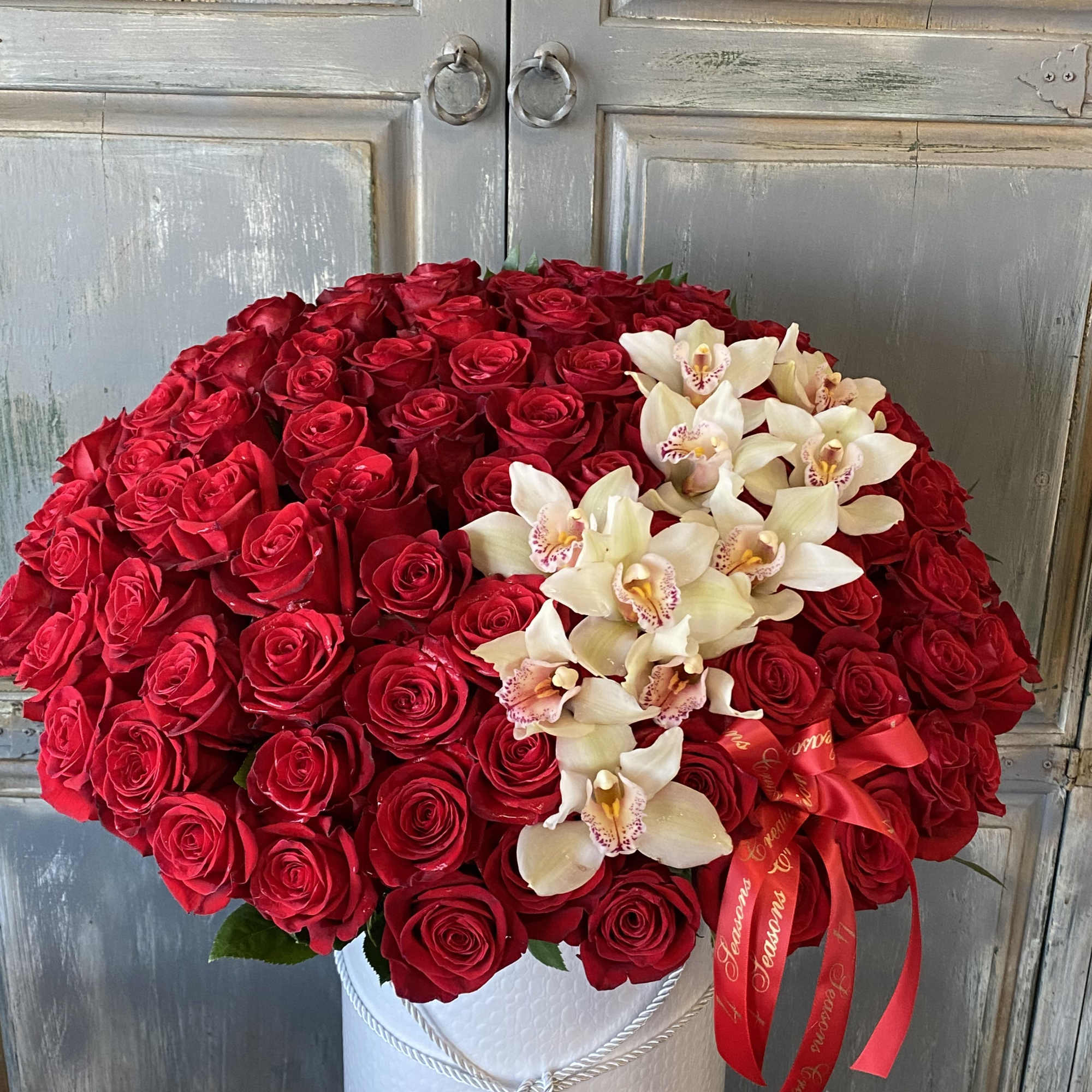 Large bouquet of red roses with white orchids in a white hatbox