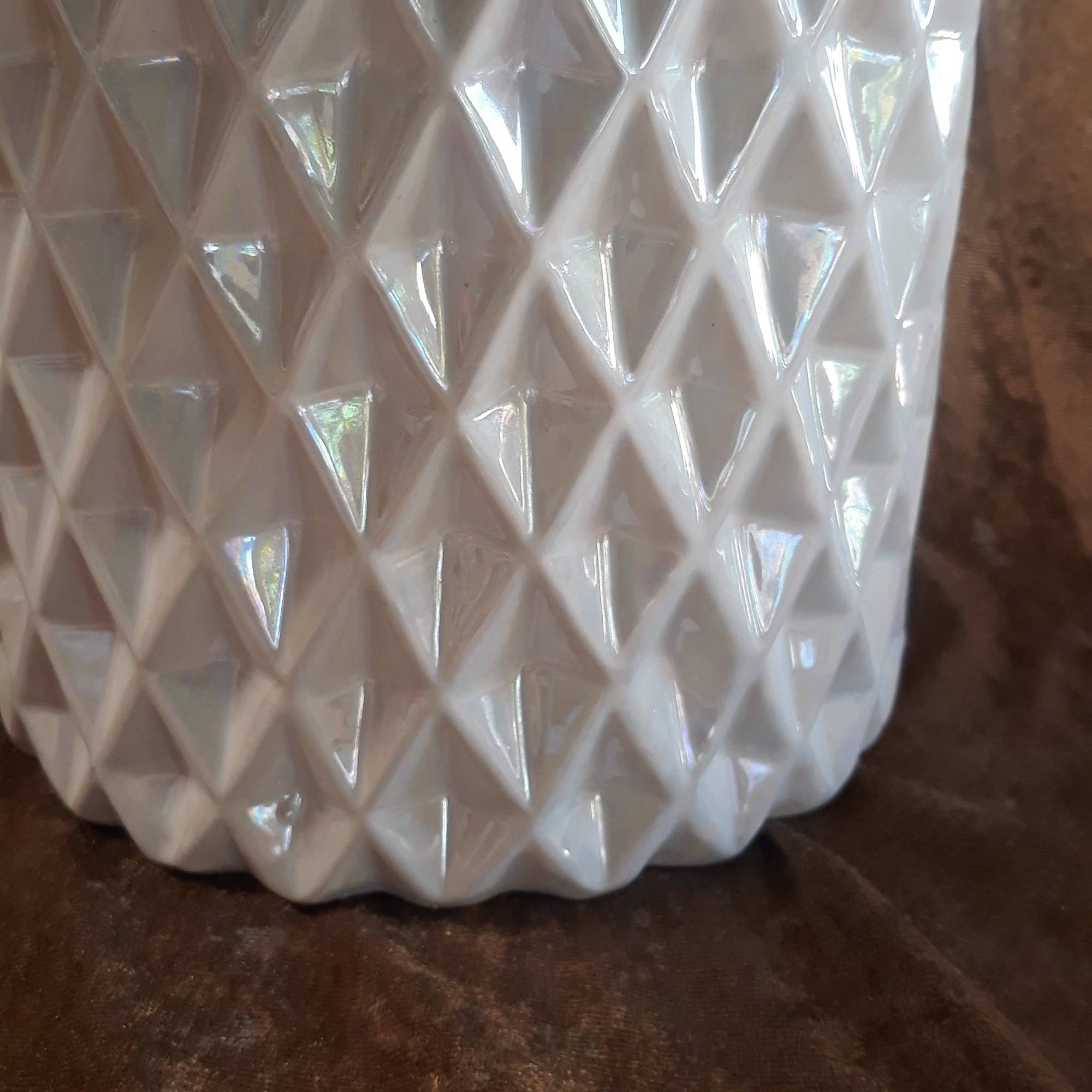 White faceted ceramic vase on a brown surface