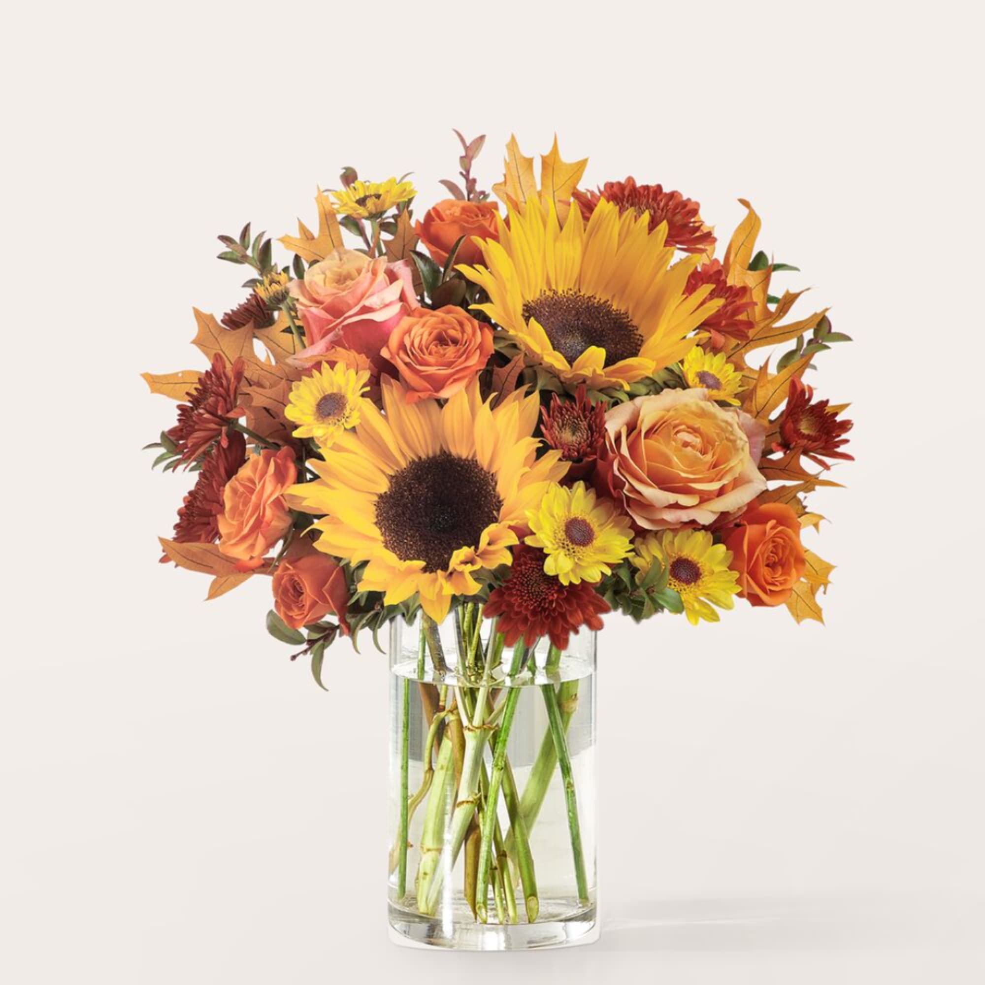 Bouquet of sunflowers and orange roses in a clear glass vase