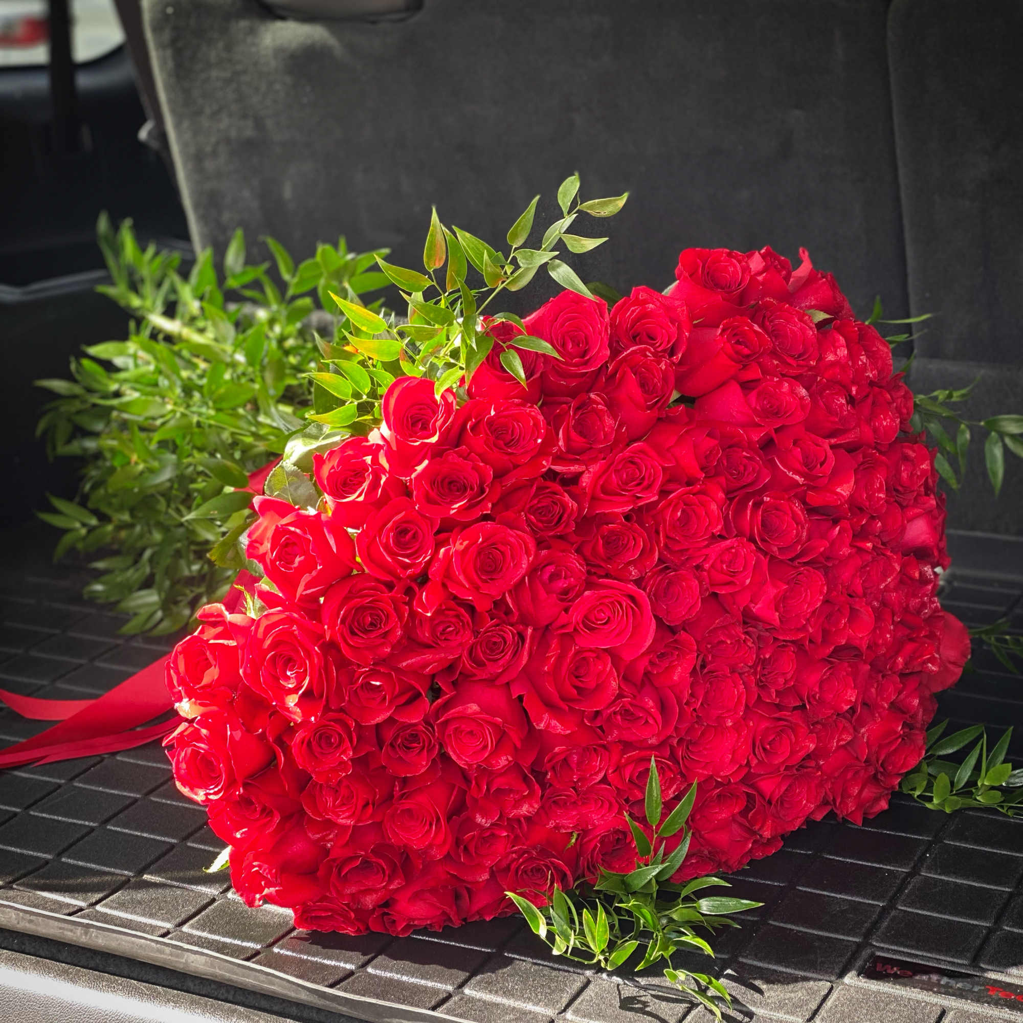 Large bouquet of red roses with greenery on a dark surface
