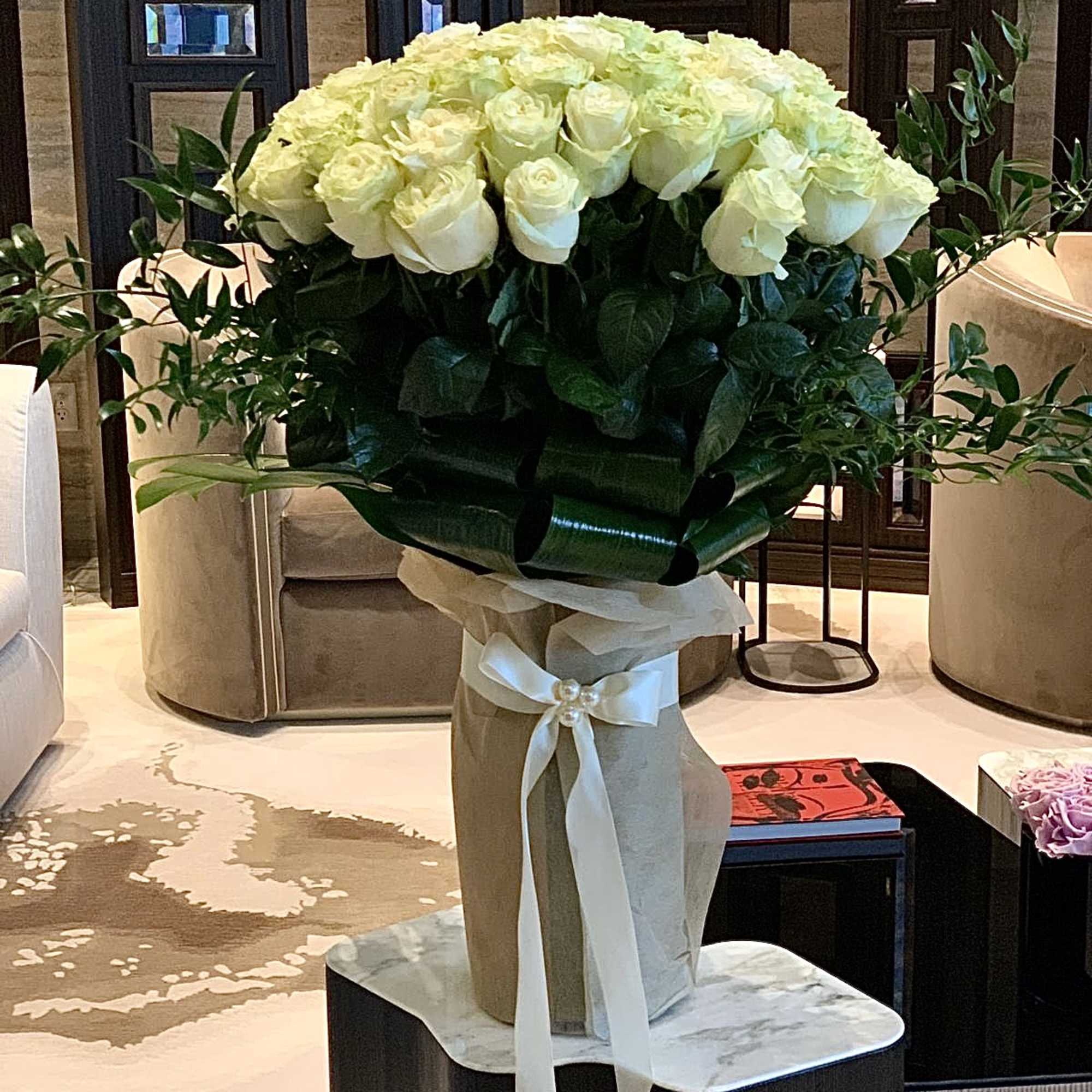 Large bouquet of white roses in a wrapped vase with a ribbon