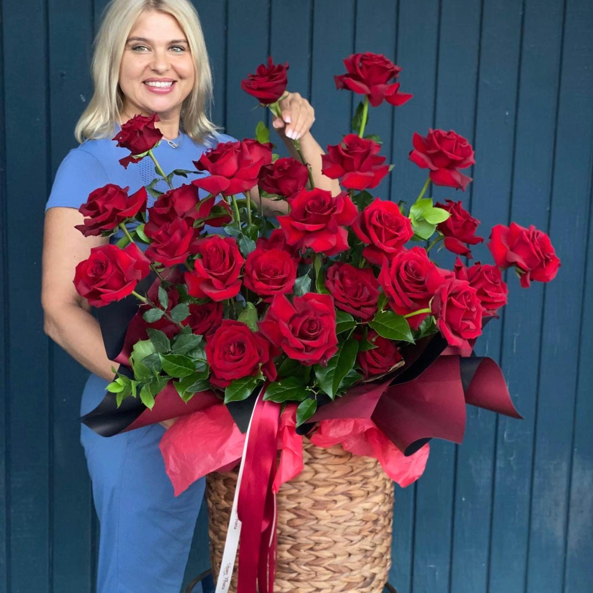 Large basket arrangement of red roses with ribbon accents