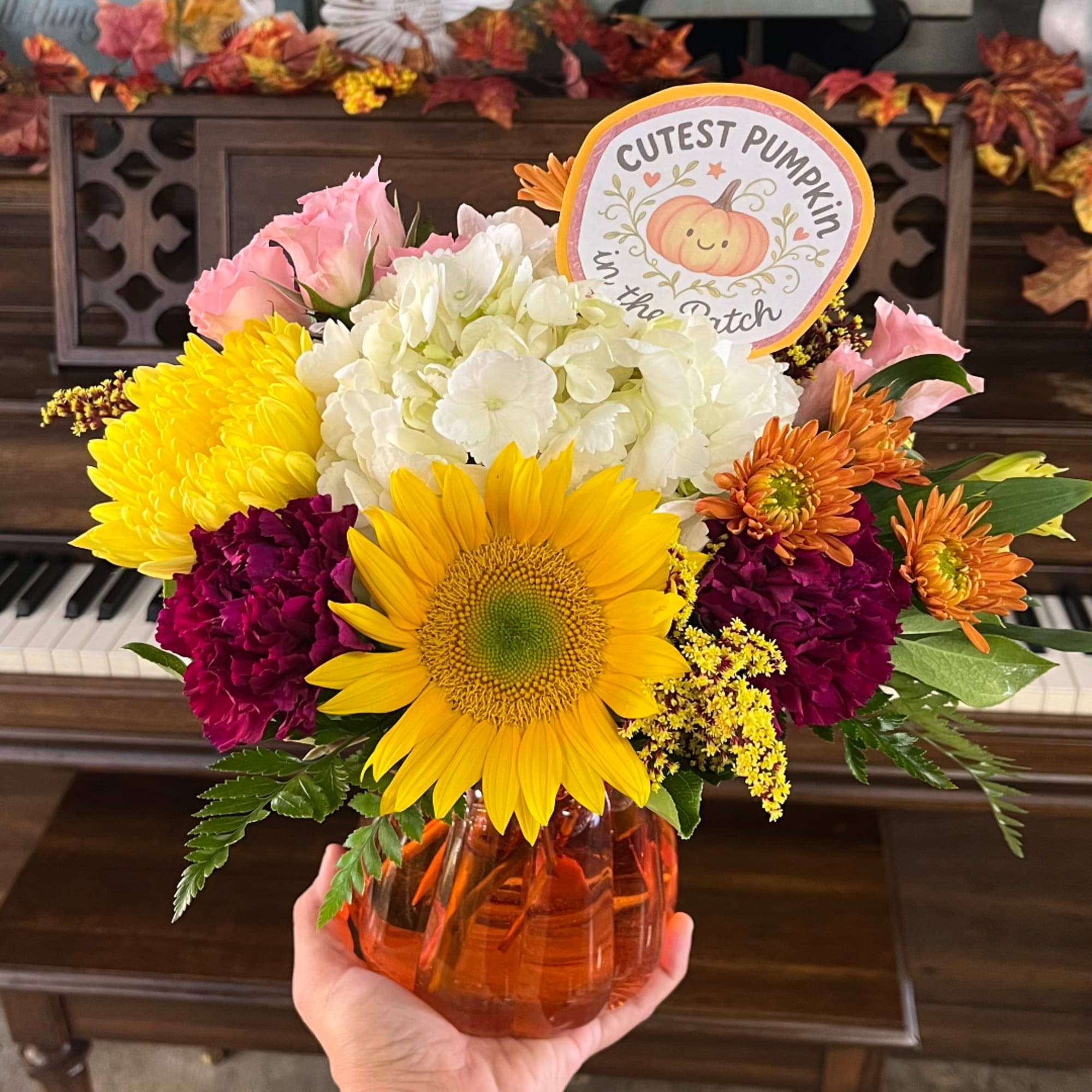 Fall bouquet in an orange vase with a pumpkin sign