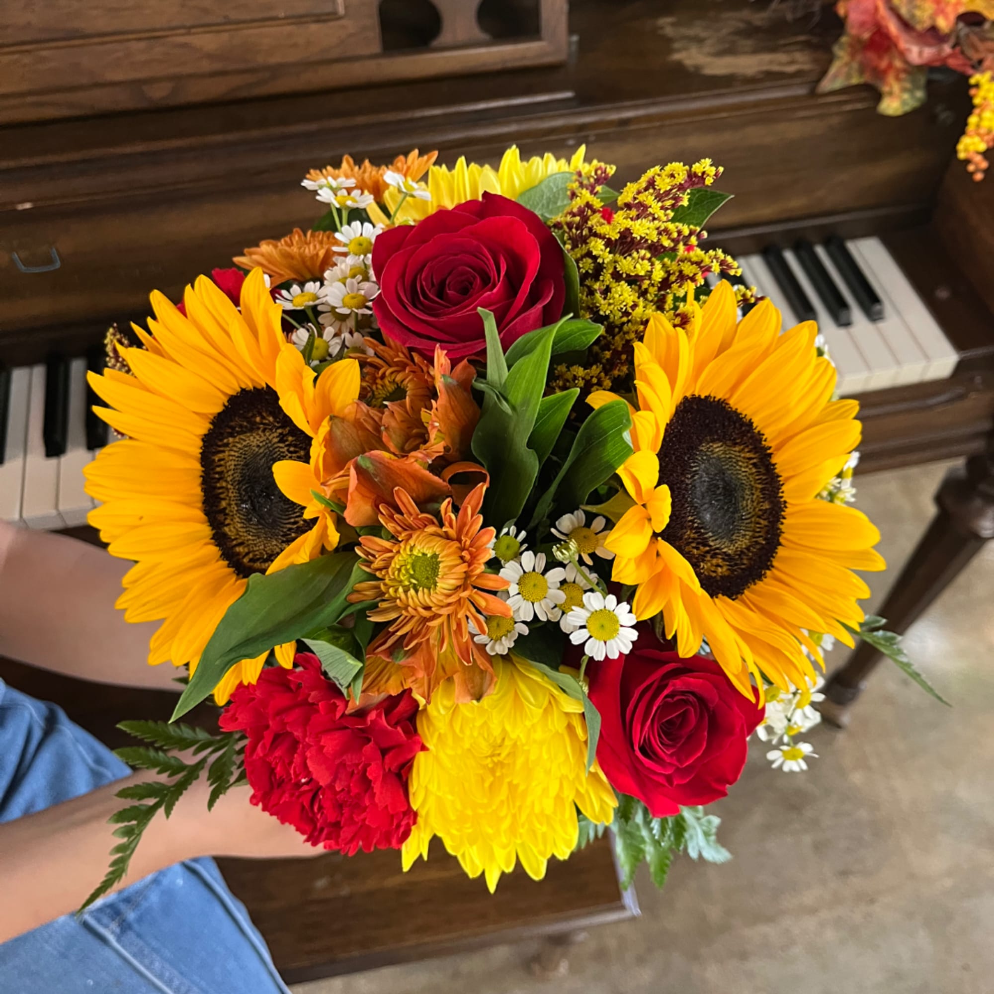 Handheld bouquet with sunflowers, red roses, and mixed blooms