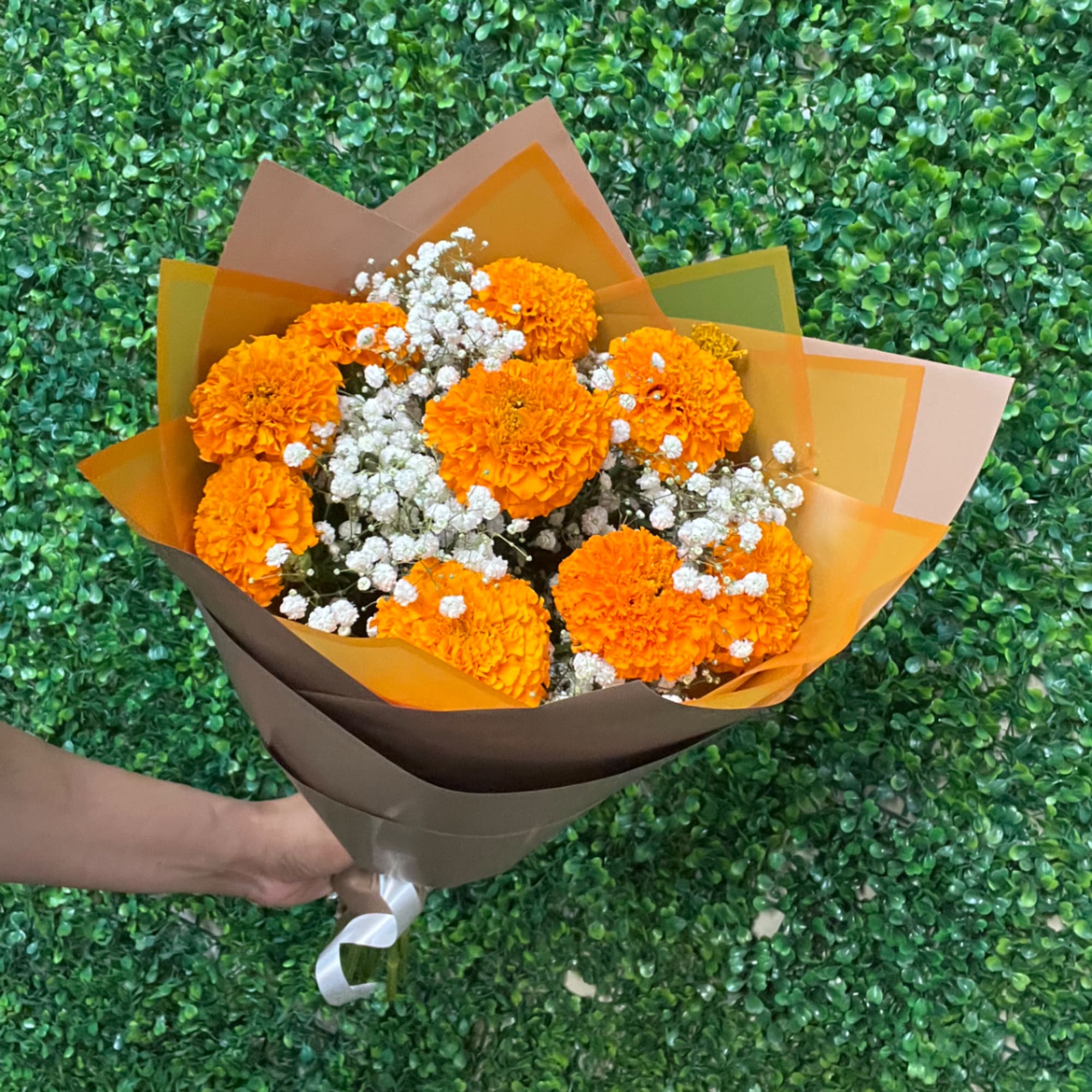Orange marigold bouquet with white baby's breath in brown and orange wrap