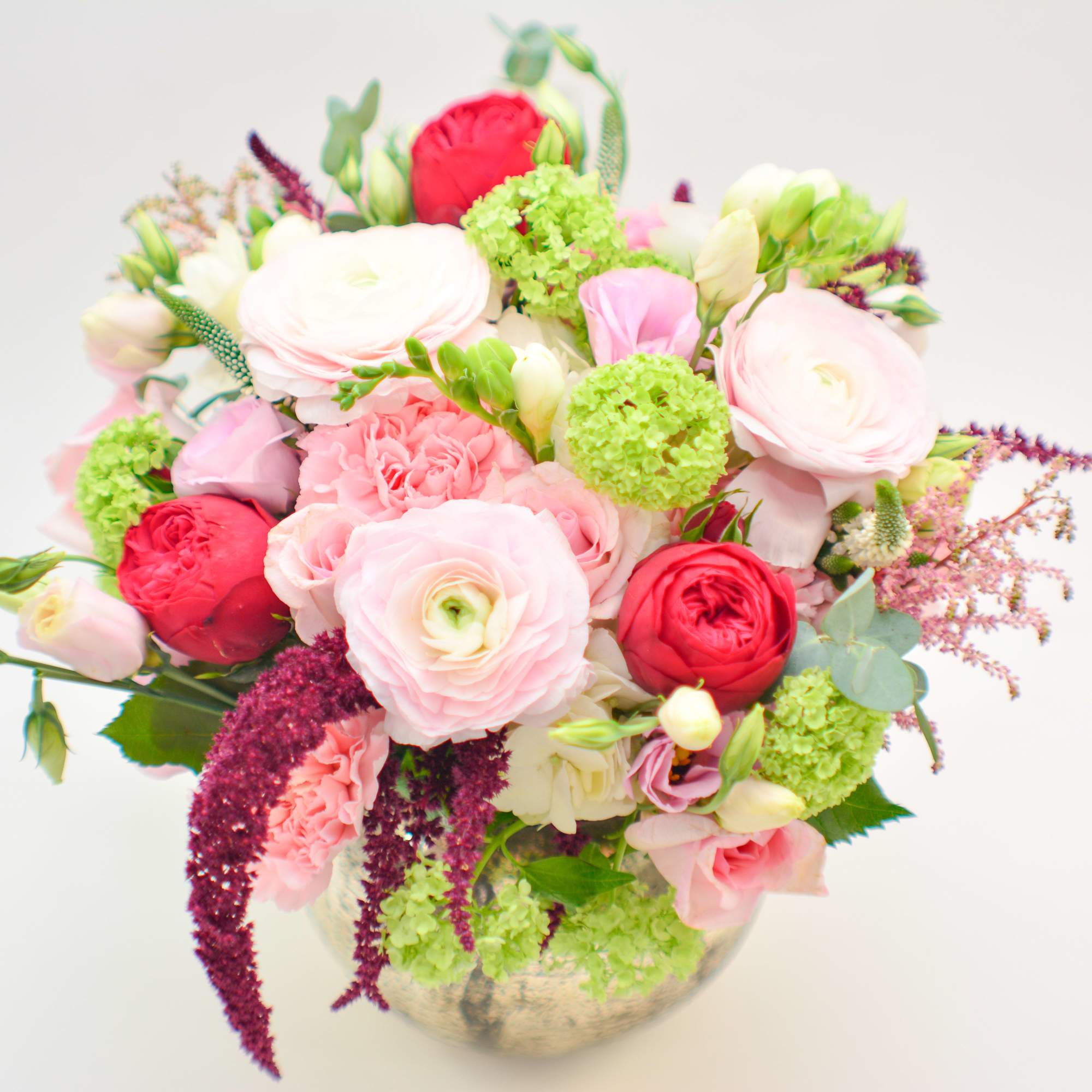 Mixed pink and red flower bouquet in a round vase