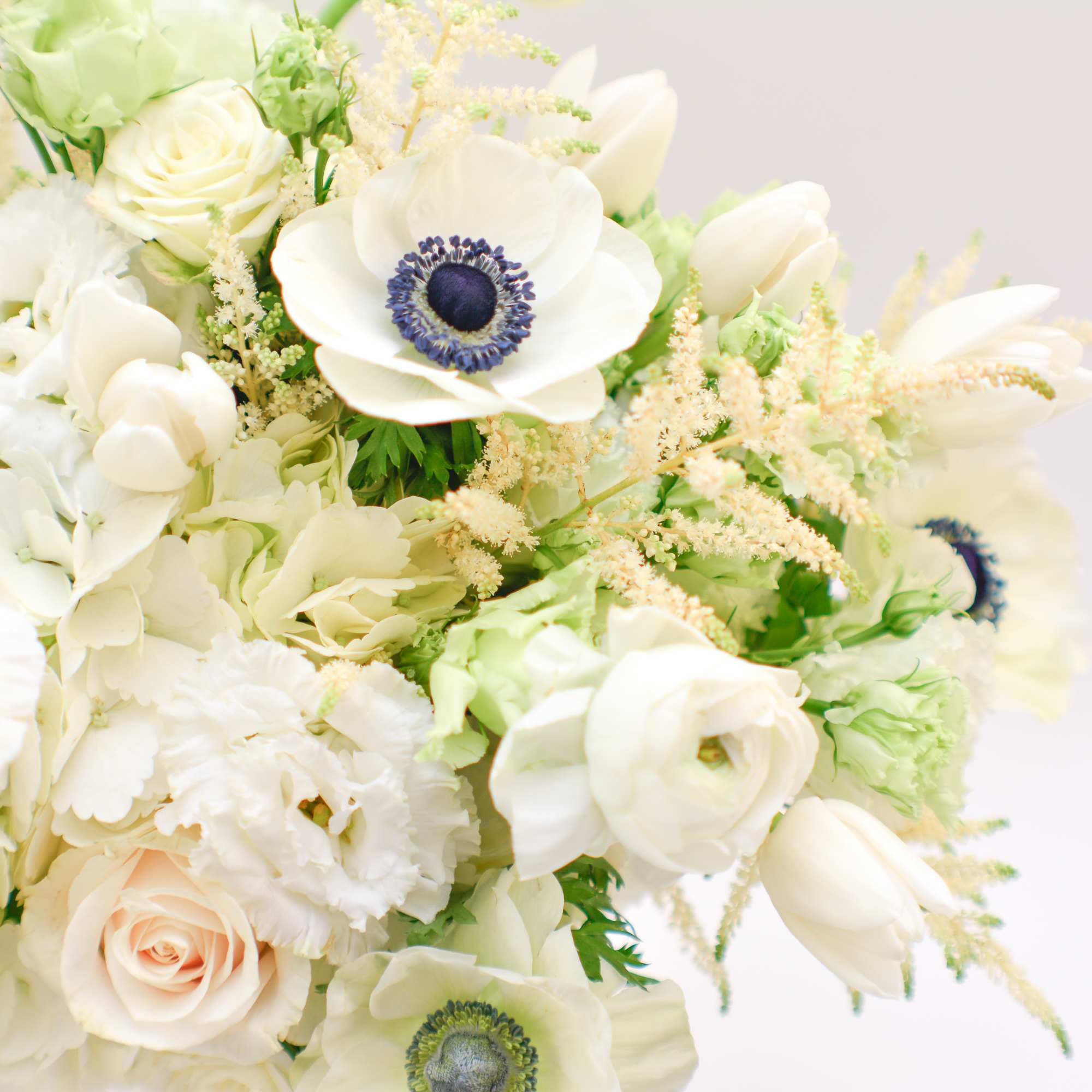 White floral bouquet with anemones, roses, and tulips