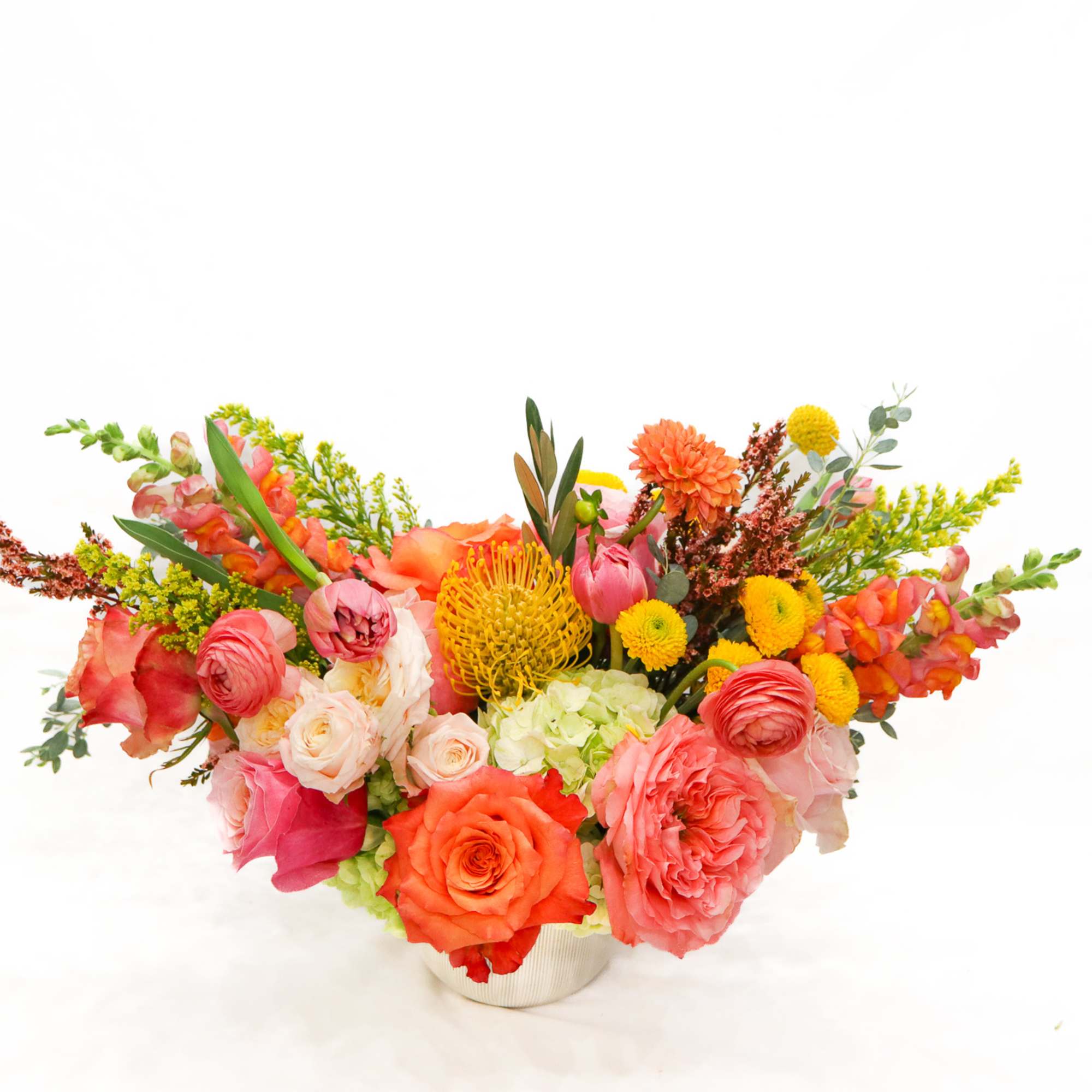 Colorful mixed flower arrangement in a low white vase