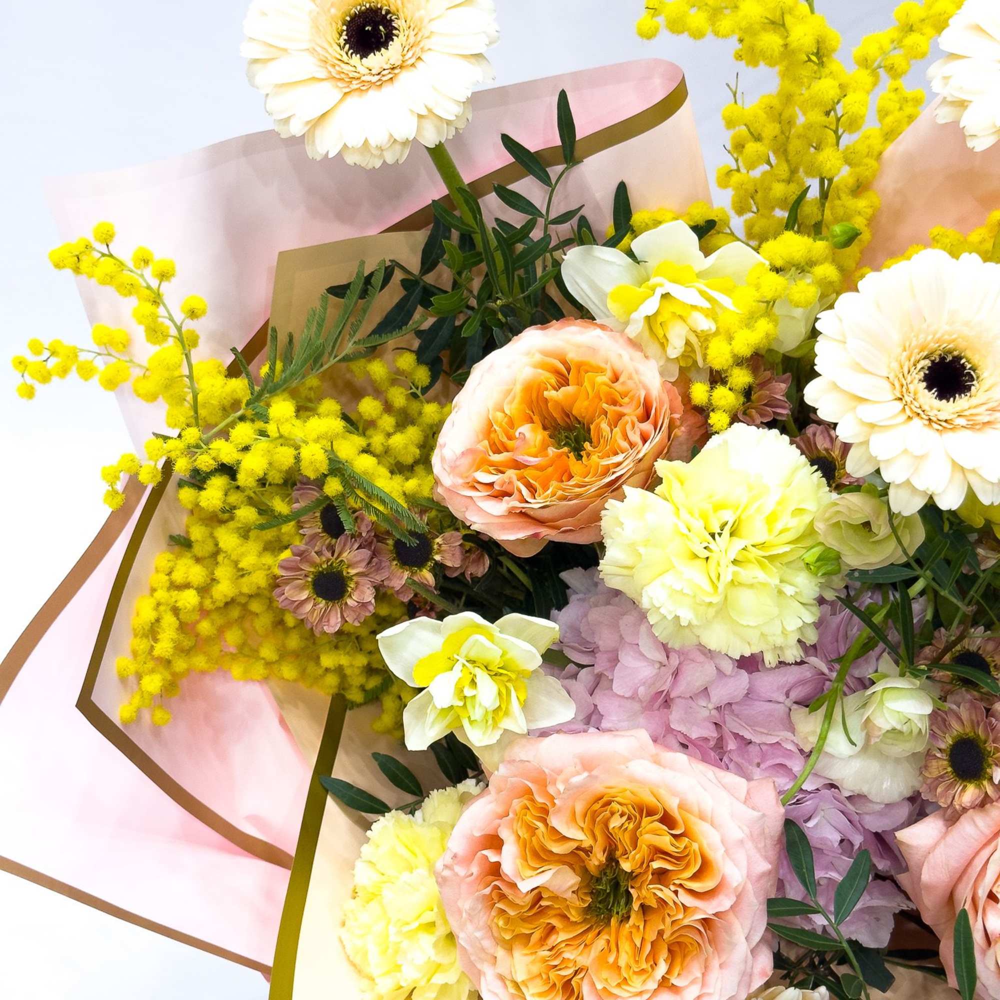 Bouquet of cream gerbera daisies, peach roses, and yellow mimosa