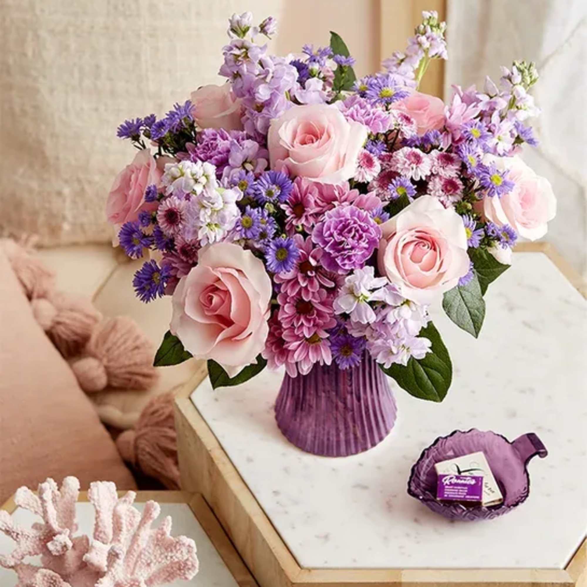 Pink roses and purple mixed flowers arranged in a purple vase