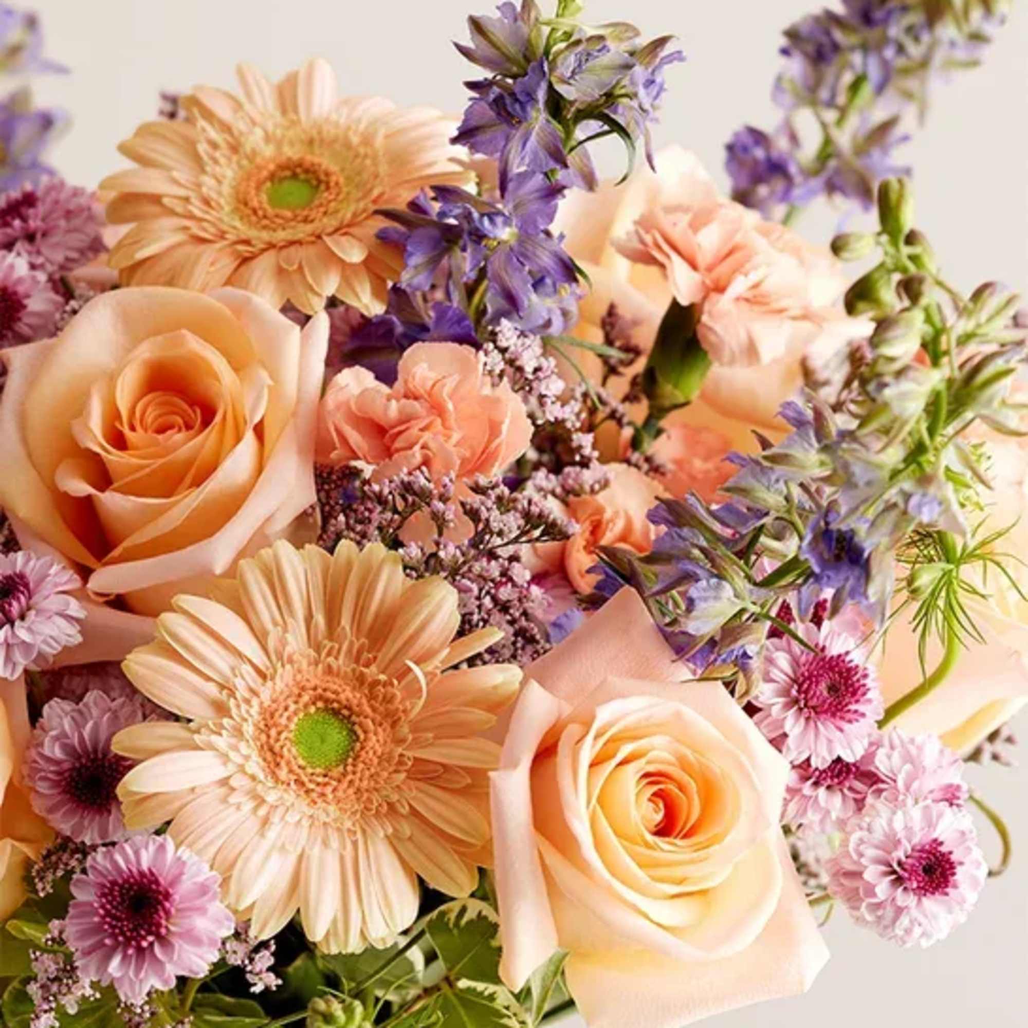 Bouquet of peach roses, gerbera daisies, and purple flowers