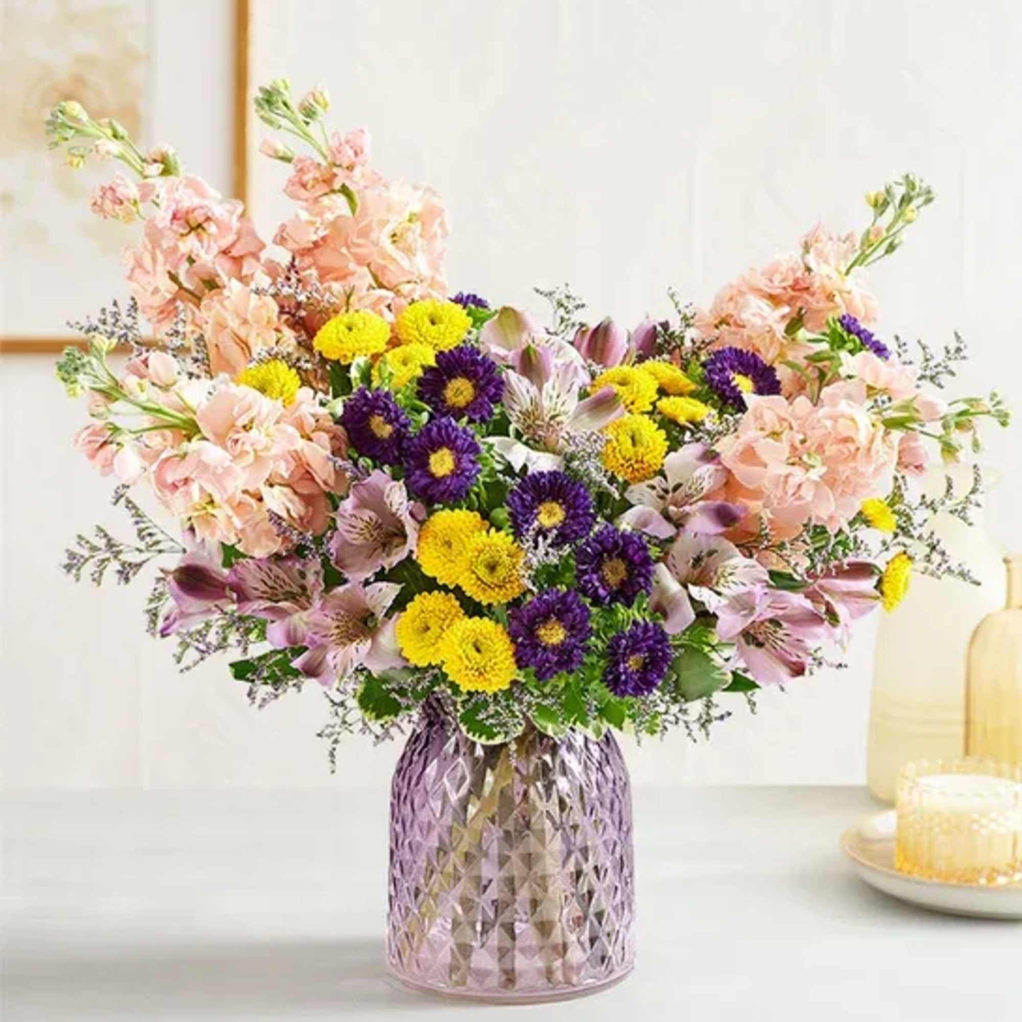 Bouquet of pink, purple, and yellow flowers in a faceted lavender vase