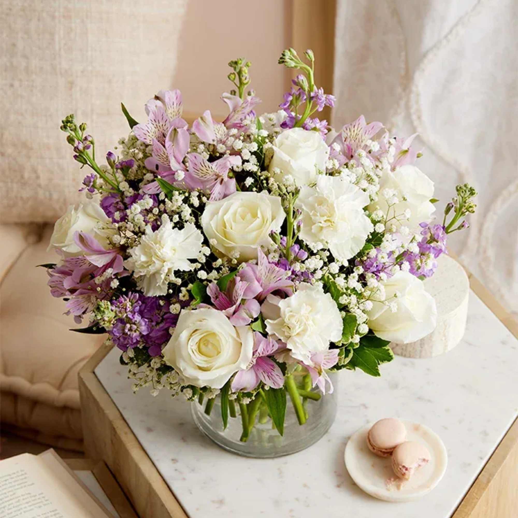 Bouquet of white roses and lavender flowers in a clear glass vase