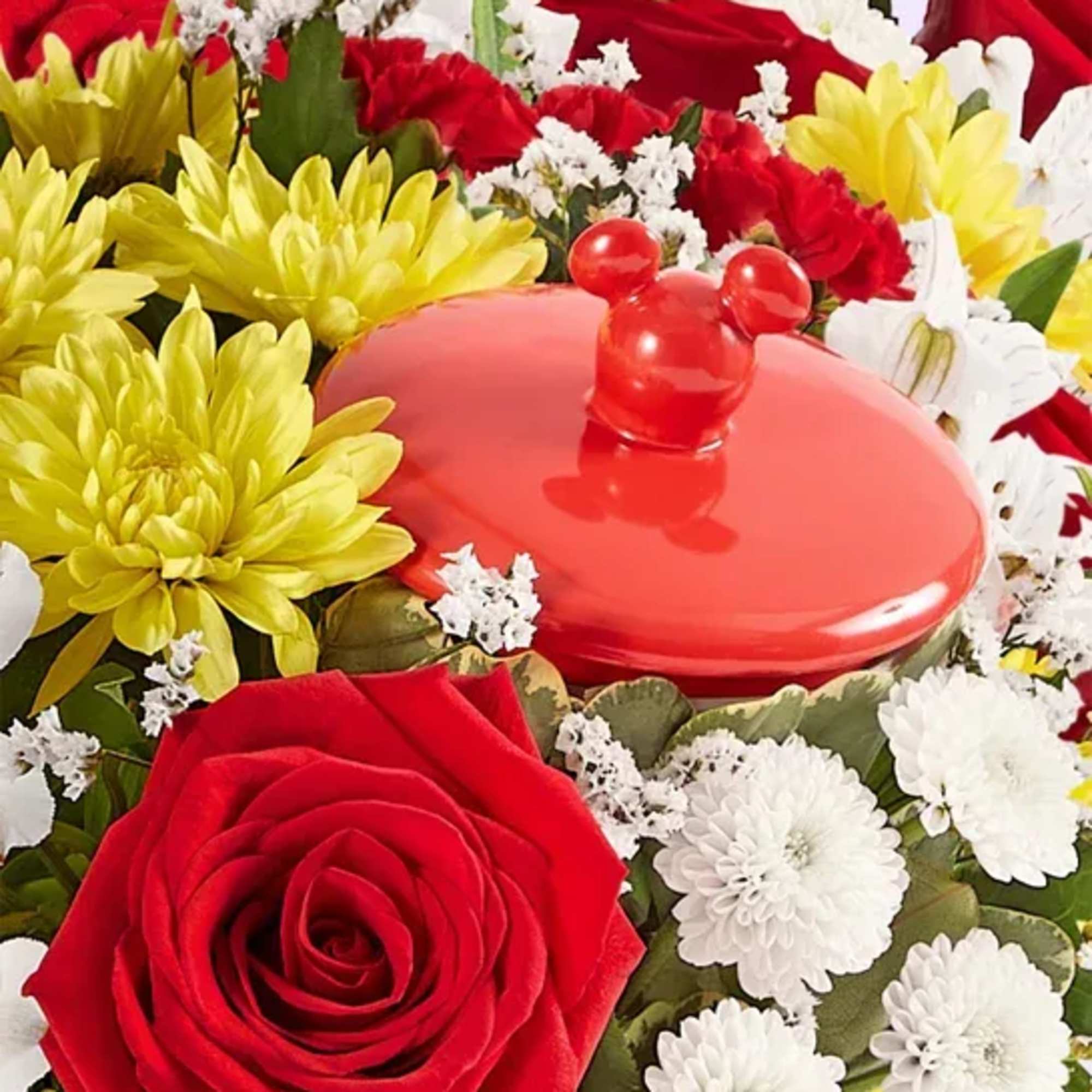 Red rose and yellow chrysanthemums around a red lidded container