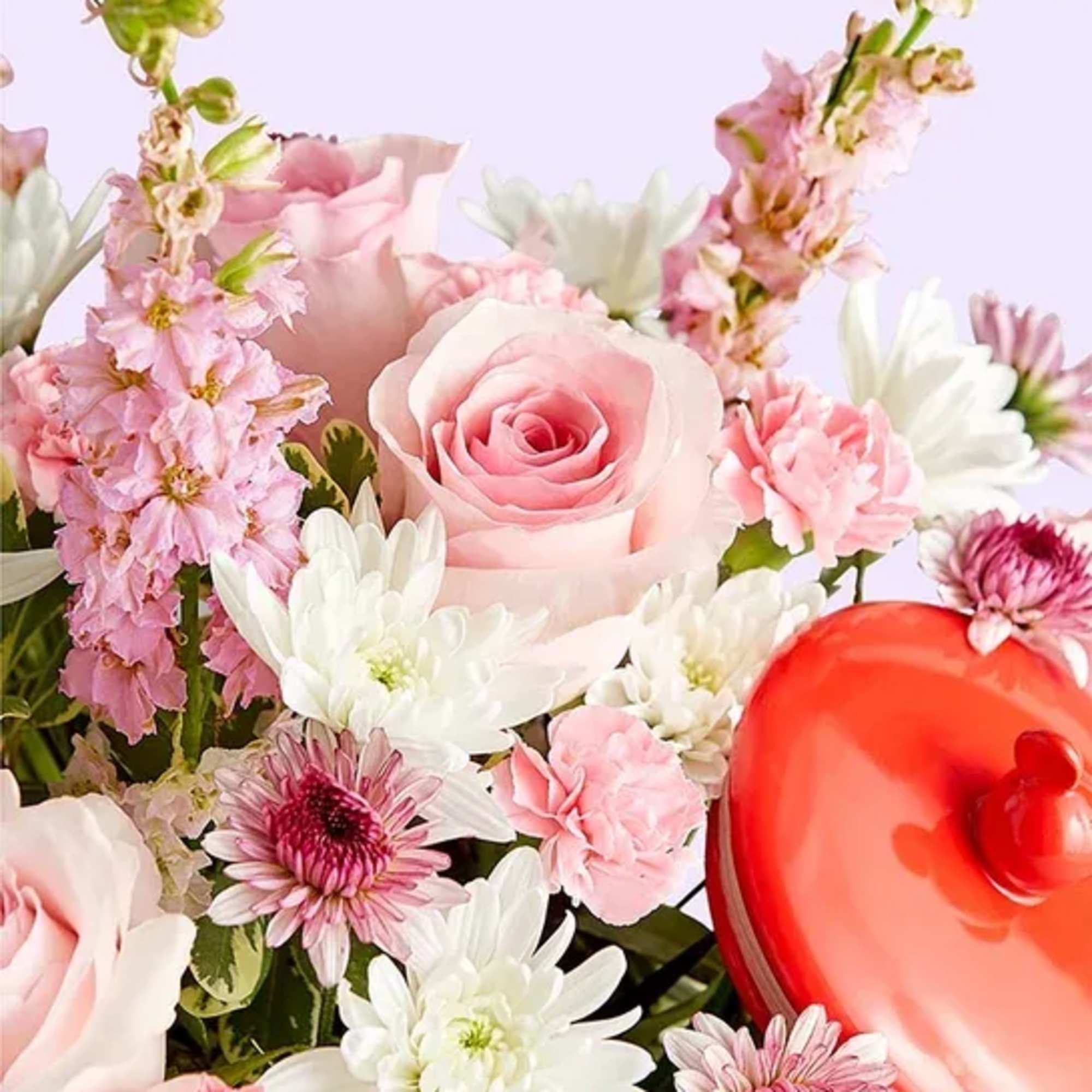 Pink and white flower arrangement with a red heart-shaped box
