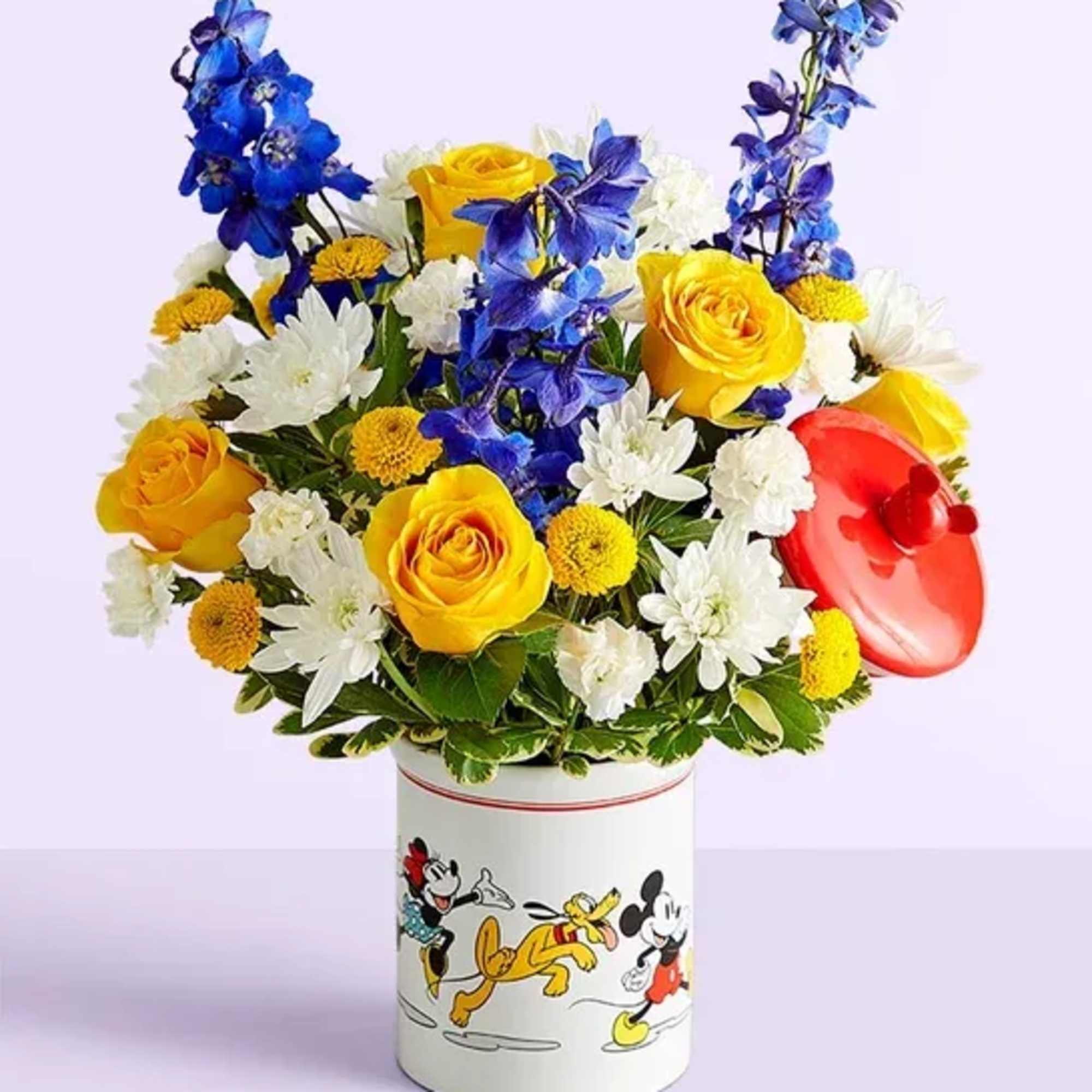 Bouquet of yellow roses, white daisies, and blue flowers in a Mickey Mouse tin
